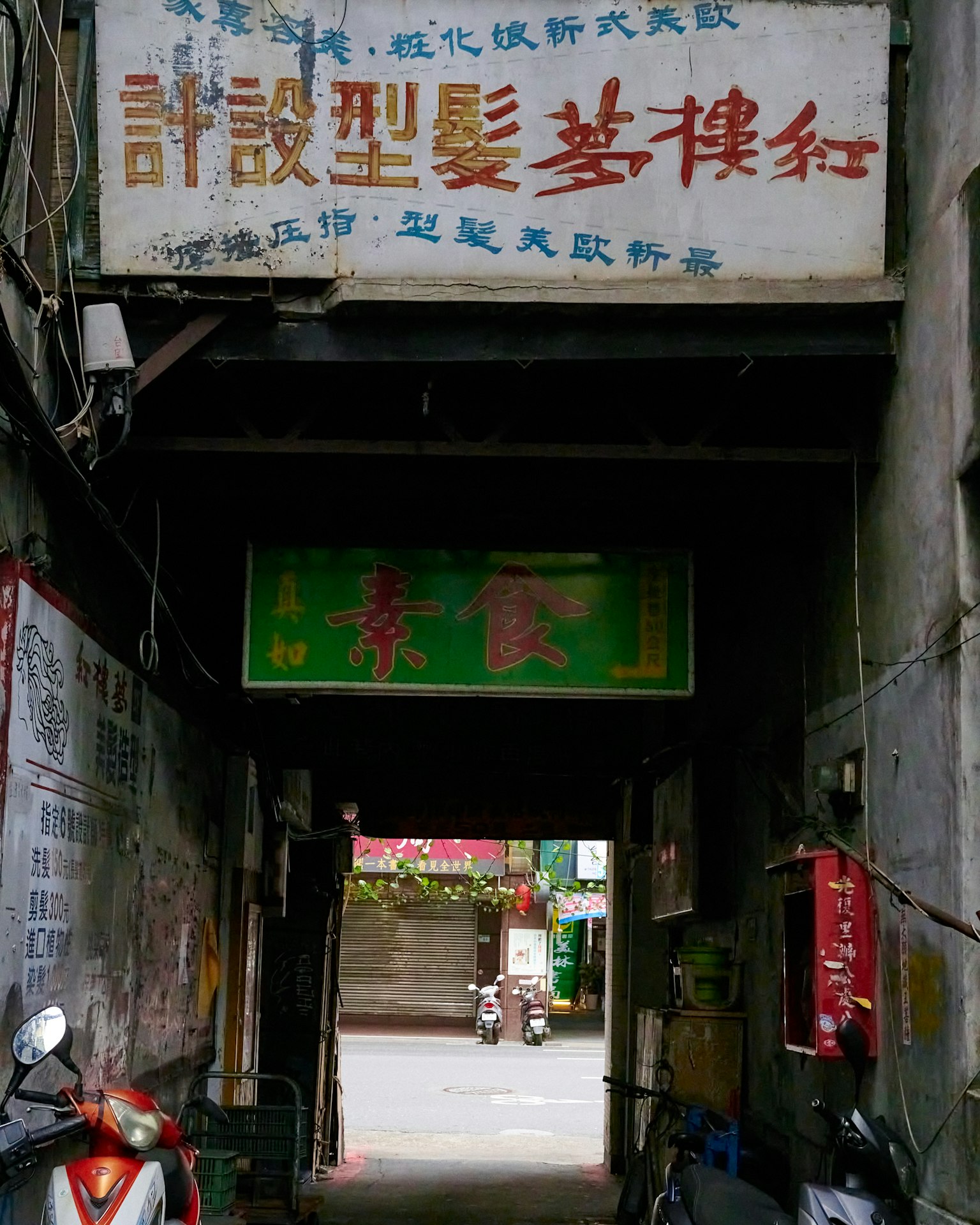 Callejón estrecho con un letrero antiguo y una señal de tienda verde