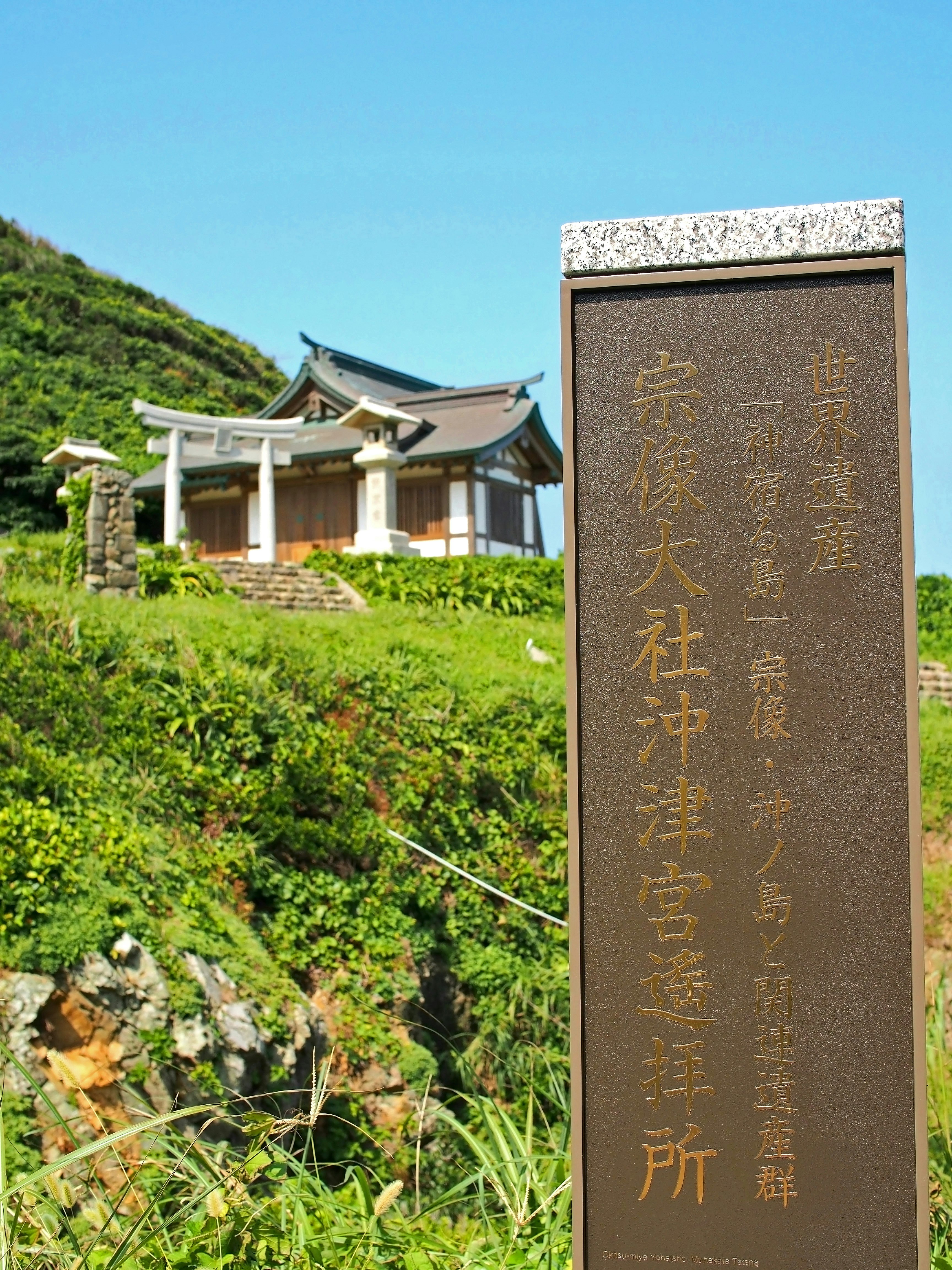 緑の丘に建つ石碑と神社の参道