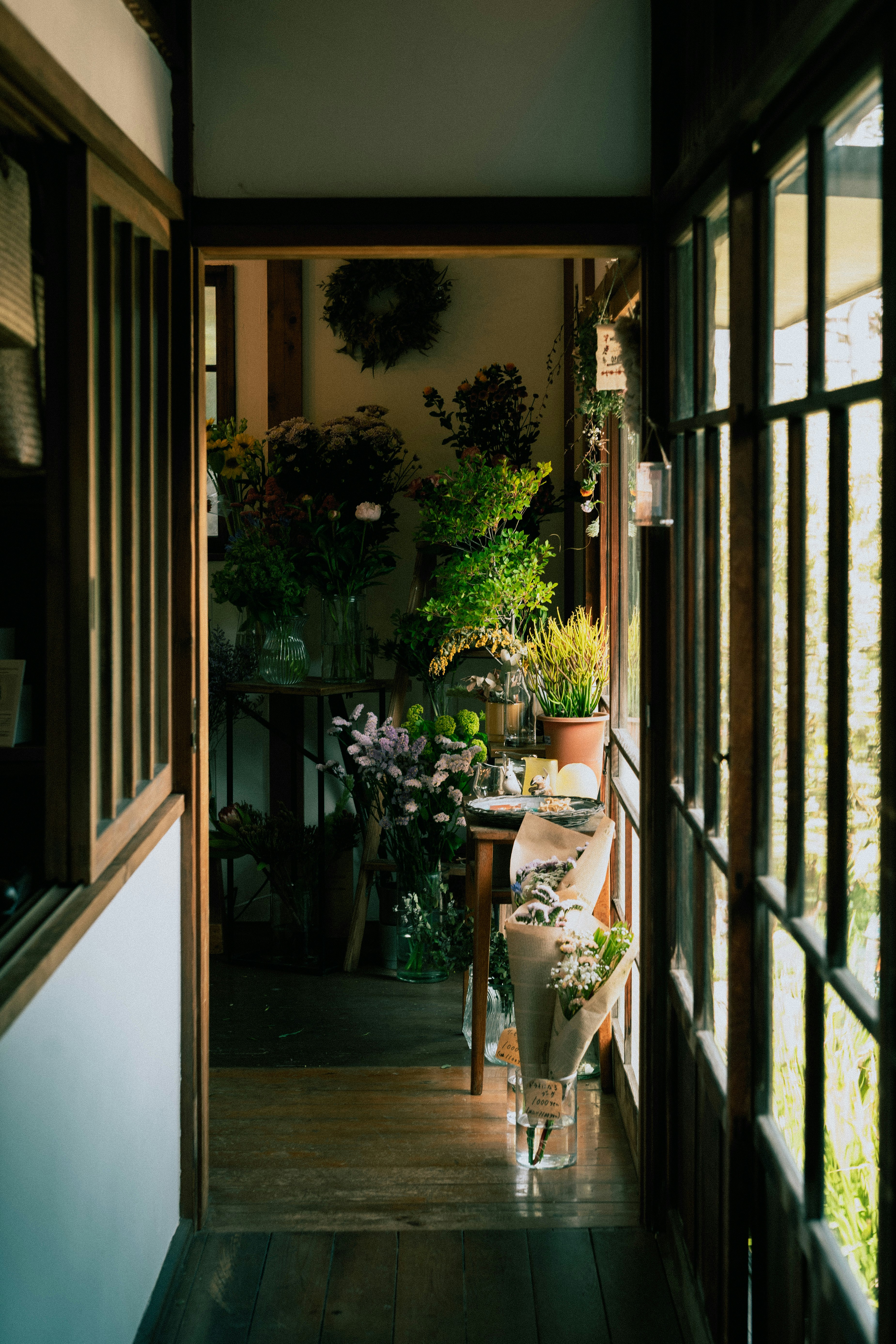 narrow flower shop corridor lined with potted plants and bouquets