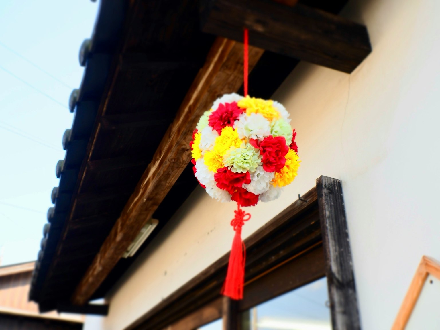 Round floral decoration in red and yellow hanging under the roof