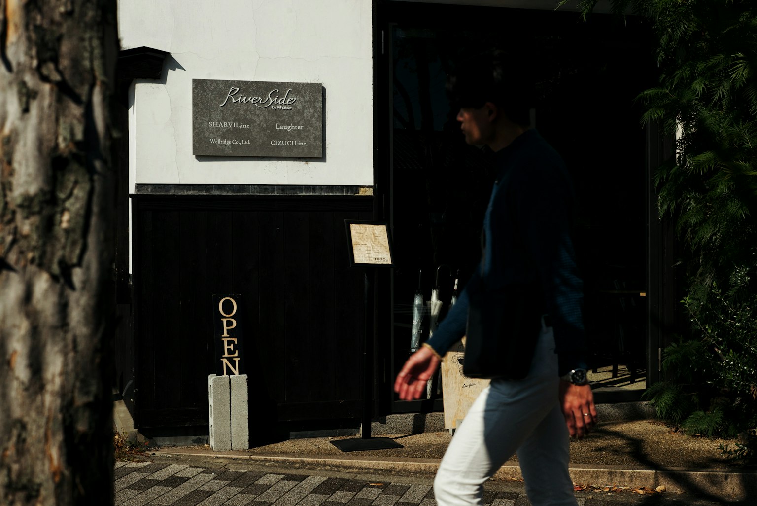 Une personne marchant devant un café avec un panneau ouvert