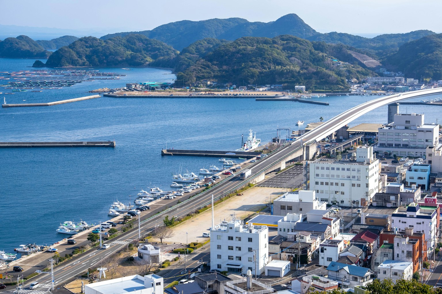 A panoramic view of a port town surrounded by sea and mountains