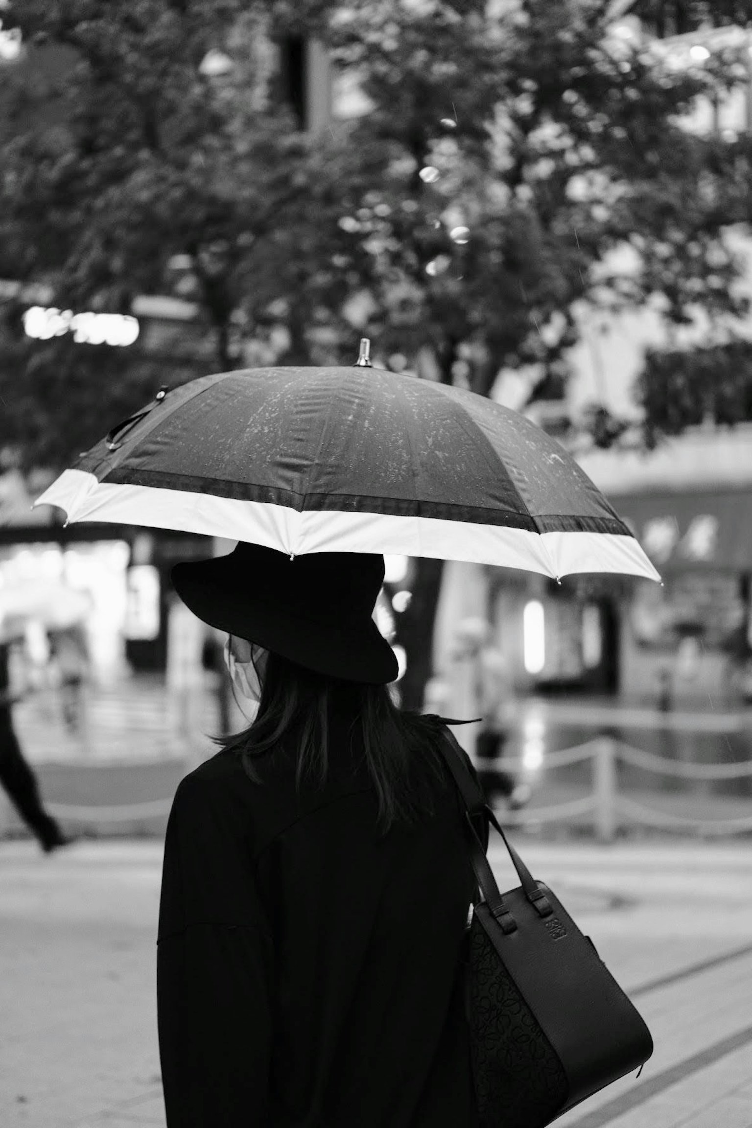 Silhouette d'une femme marchant dans la ville avec un parapluie noir