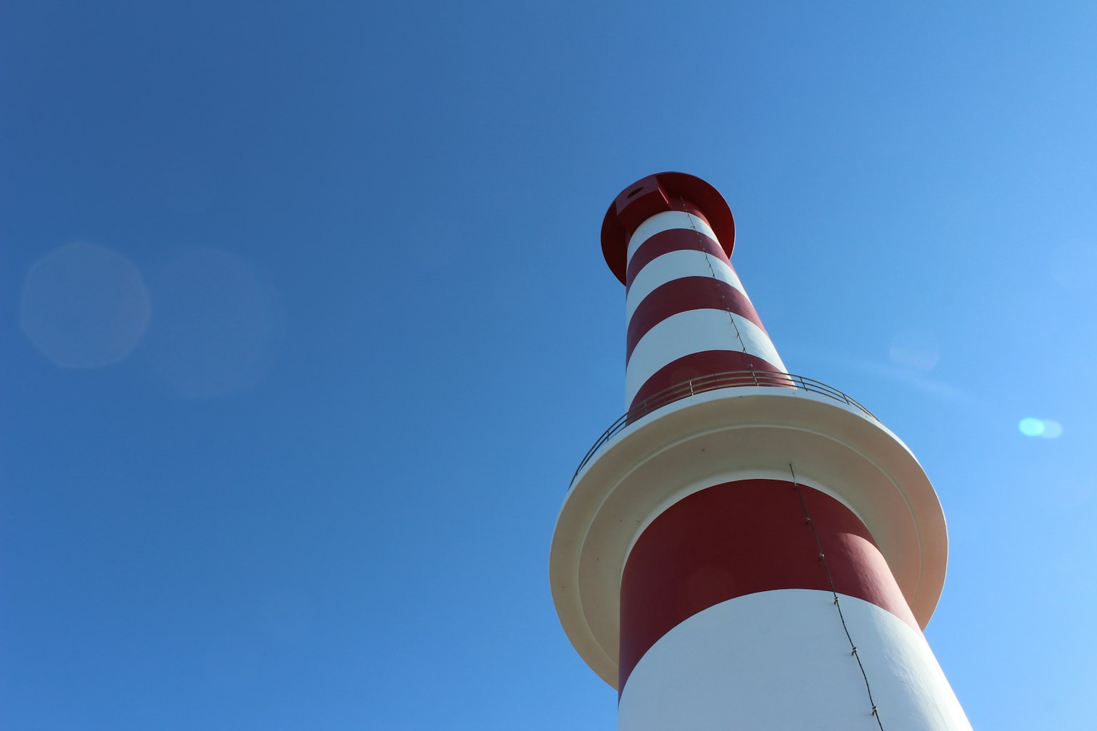 Un faro a strisce rosse e bianche che si erge contro un cielo blu chiaro
