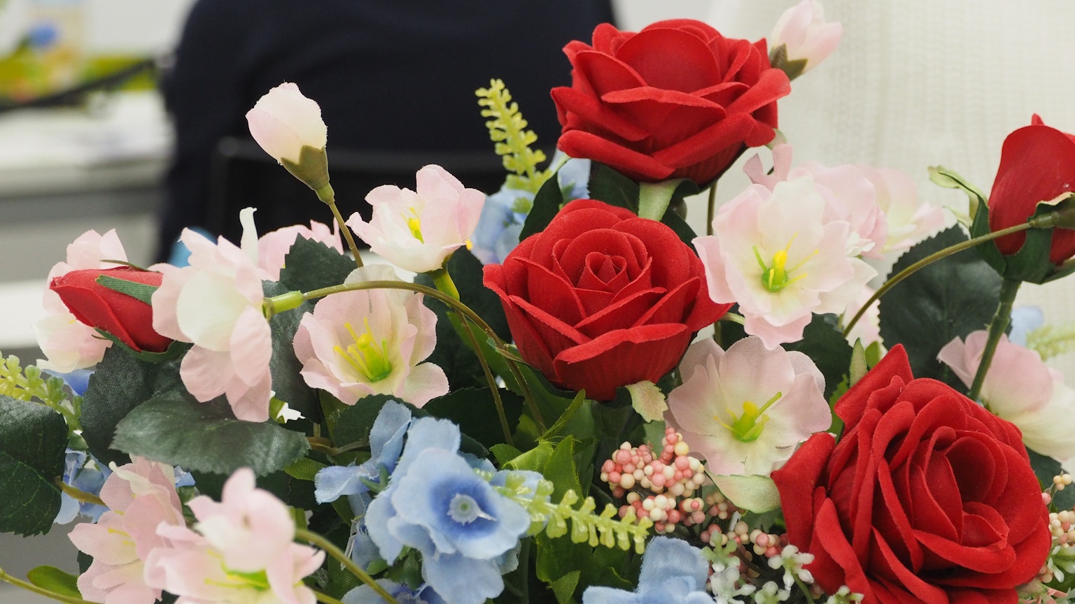 Schöner Blumenstrauß mit roten Rosen und blauen Blumen