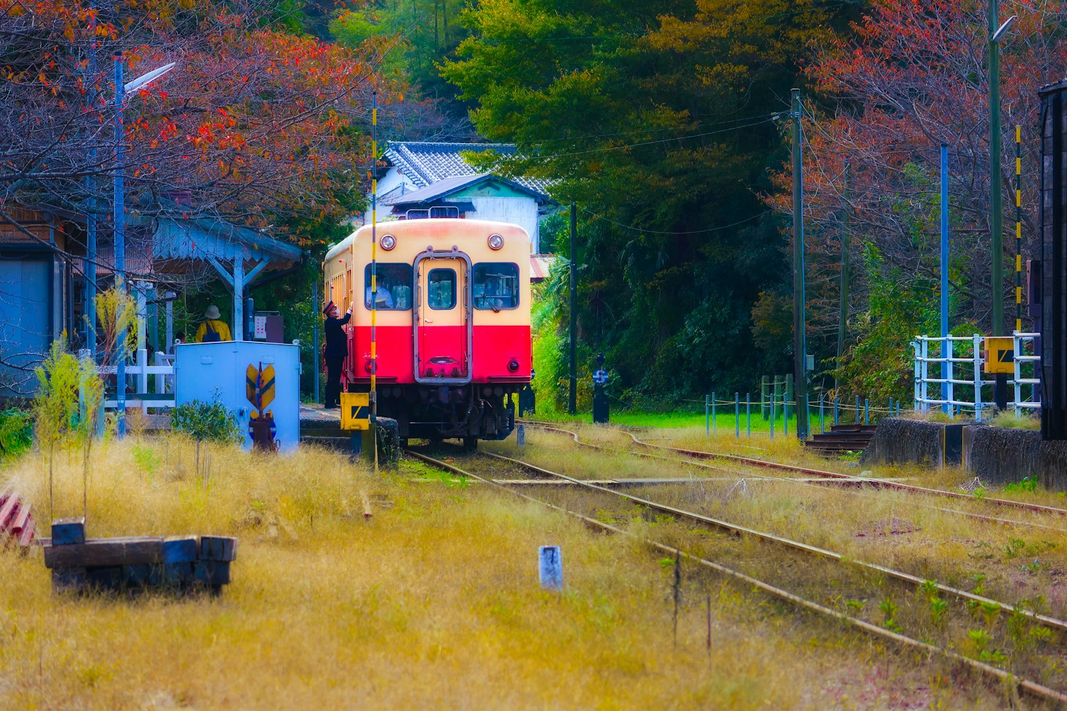 一列紅色火車停在一個被秋天景色環繞的車站