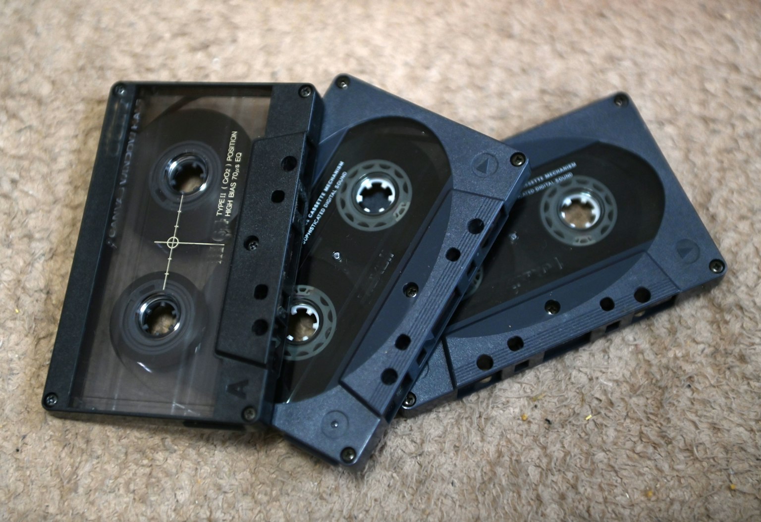 Three black cassette tapes lying on a carpeted surface