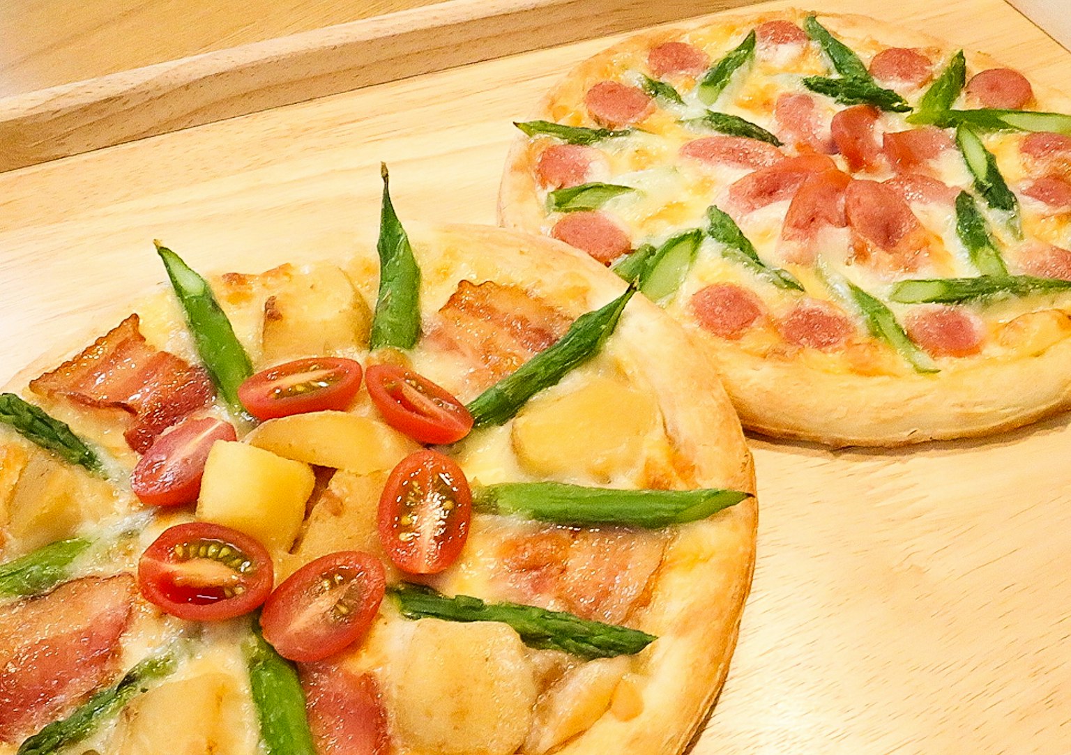 Dua pizza lezat disusun di atas nampan kayu