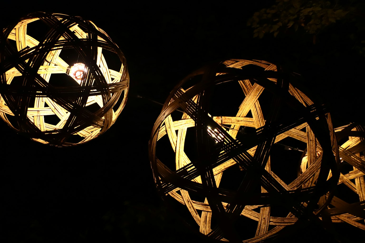 Exhibición de lámparas esféricas de madera iluminadas sobre un fondo oscuro