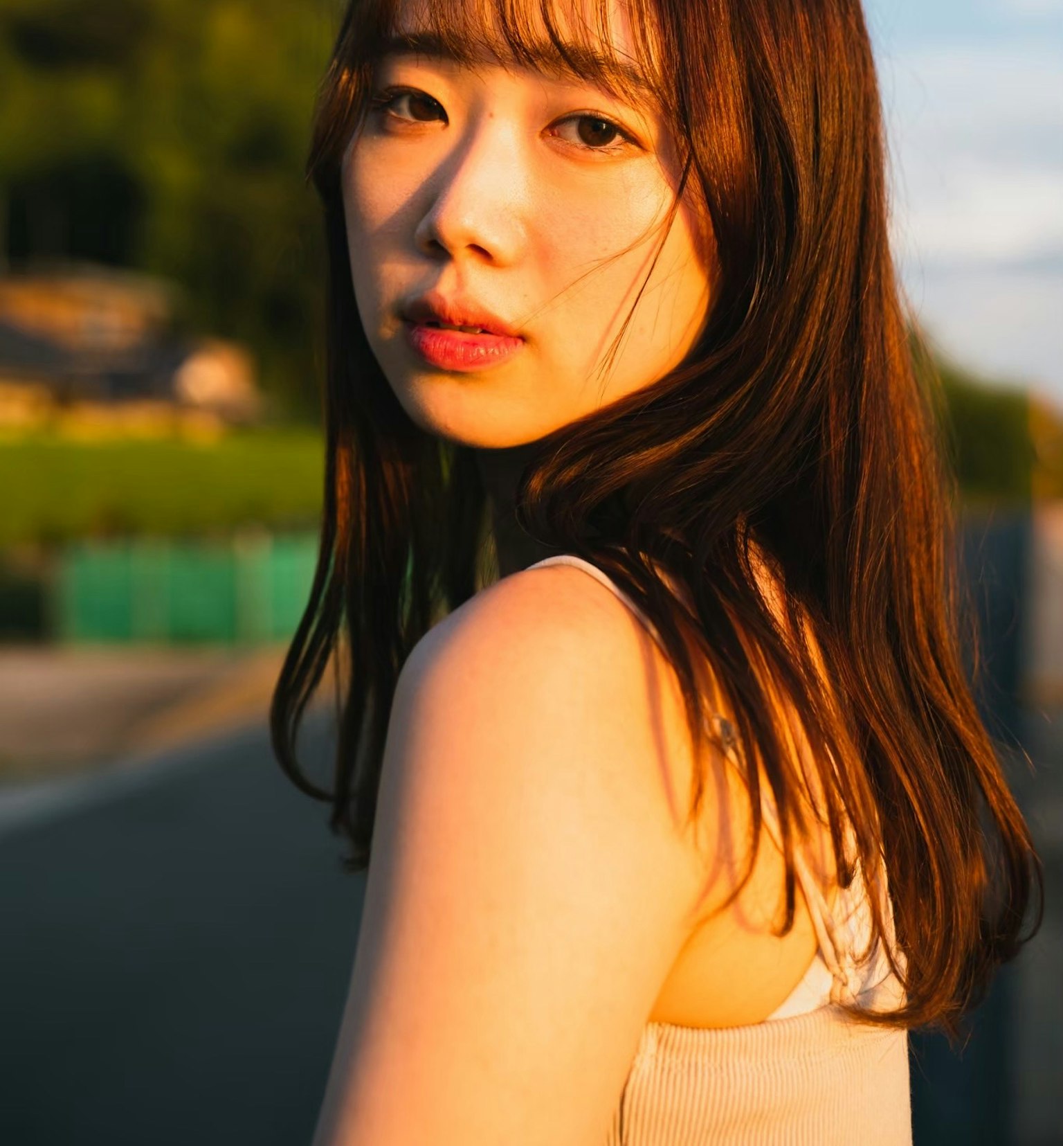 Retrato de una mujer bañada en luz de atardecer con cabello largo y lacio y un fondo natural