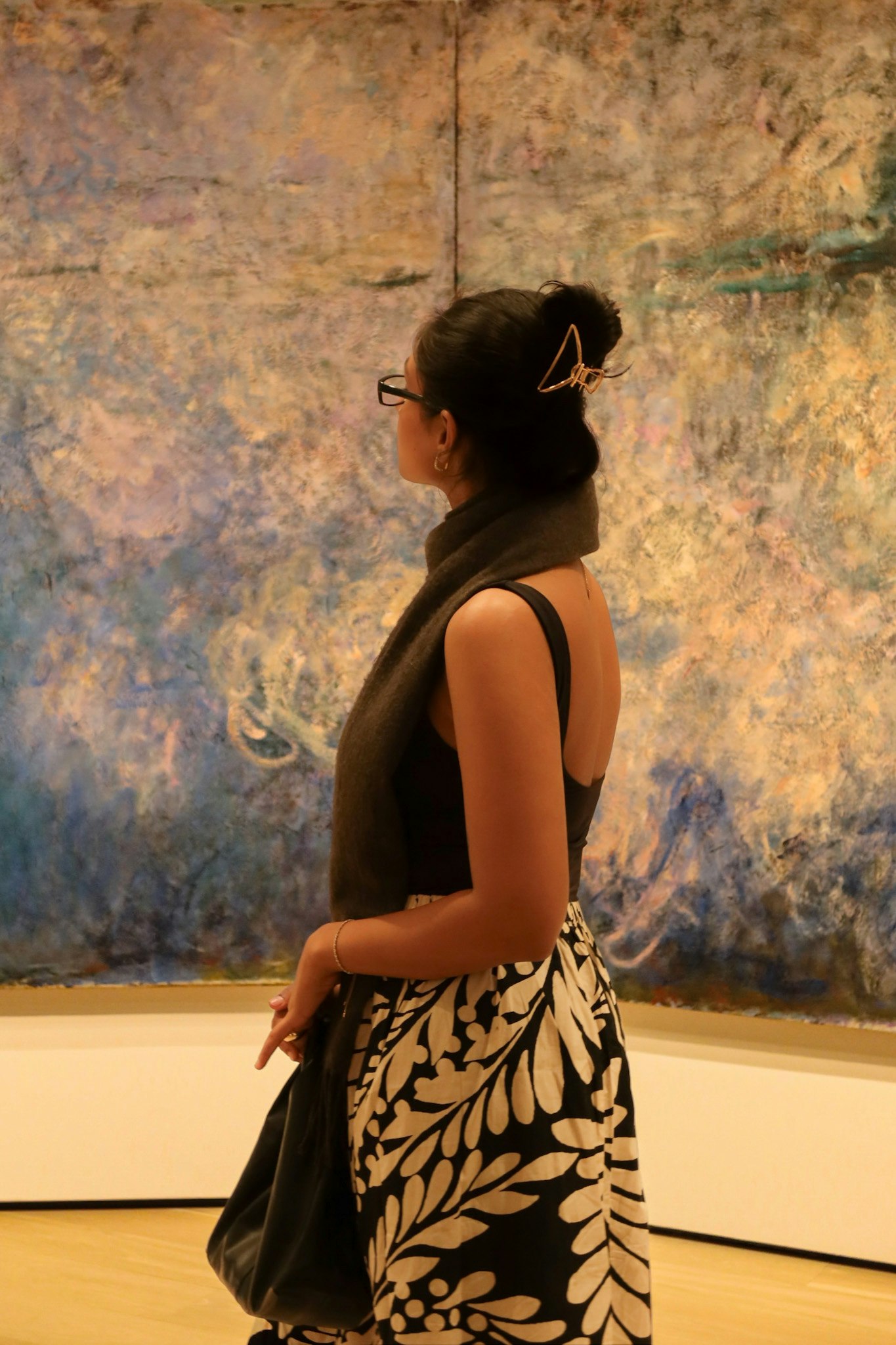 壁画の前で後ろ姿の女性が立つ美術館の展示空間