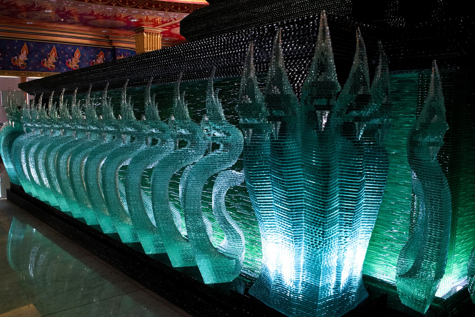 Opera d'arte con forme scultoree a forma di serpente illuminate da luce turchese