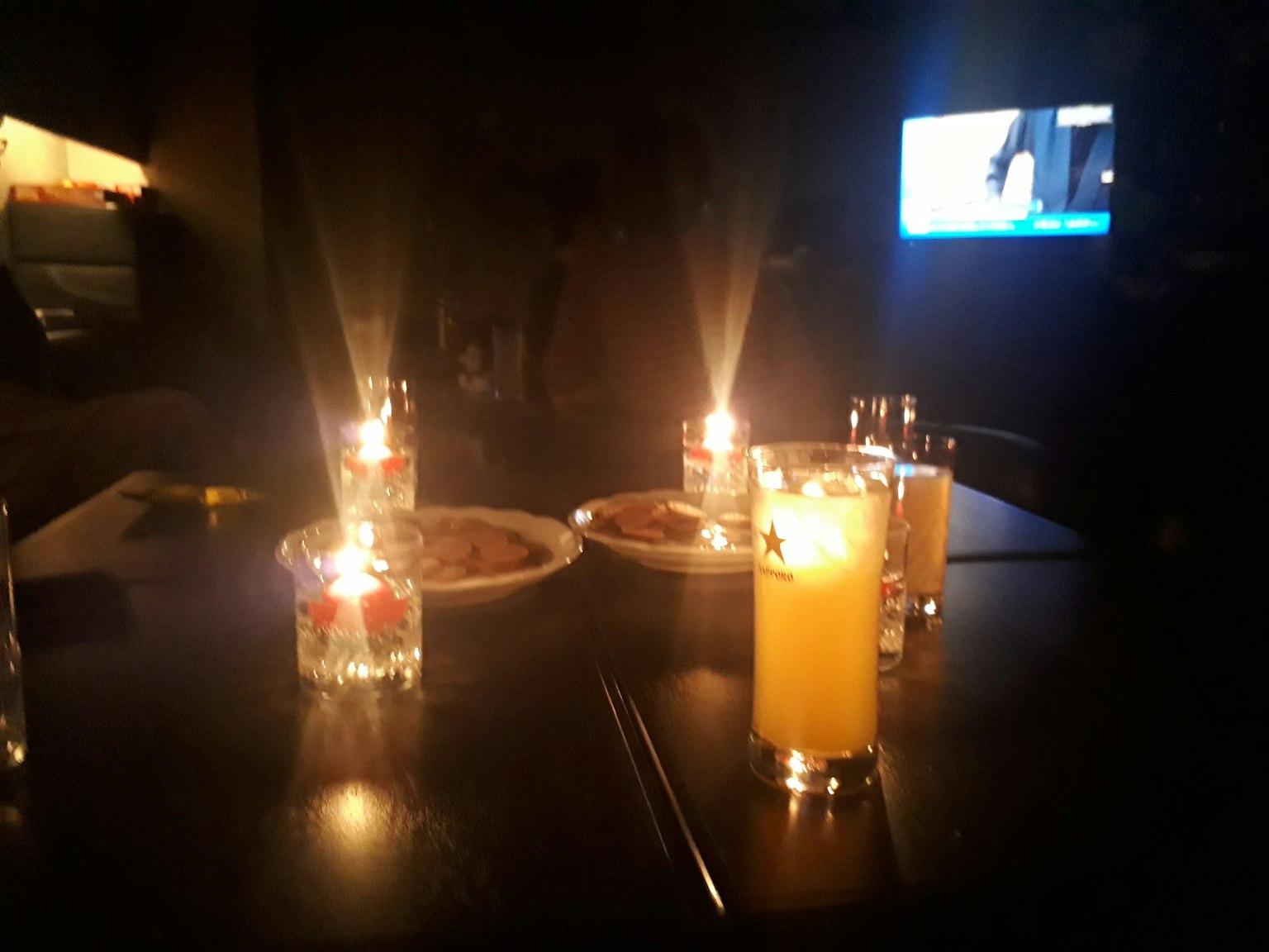 Table setting with candles and orange juice in a dimly lit room