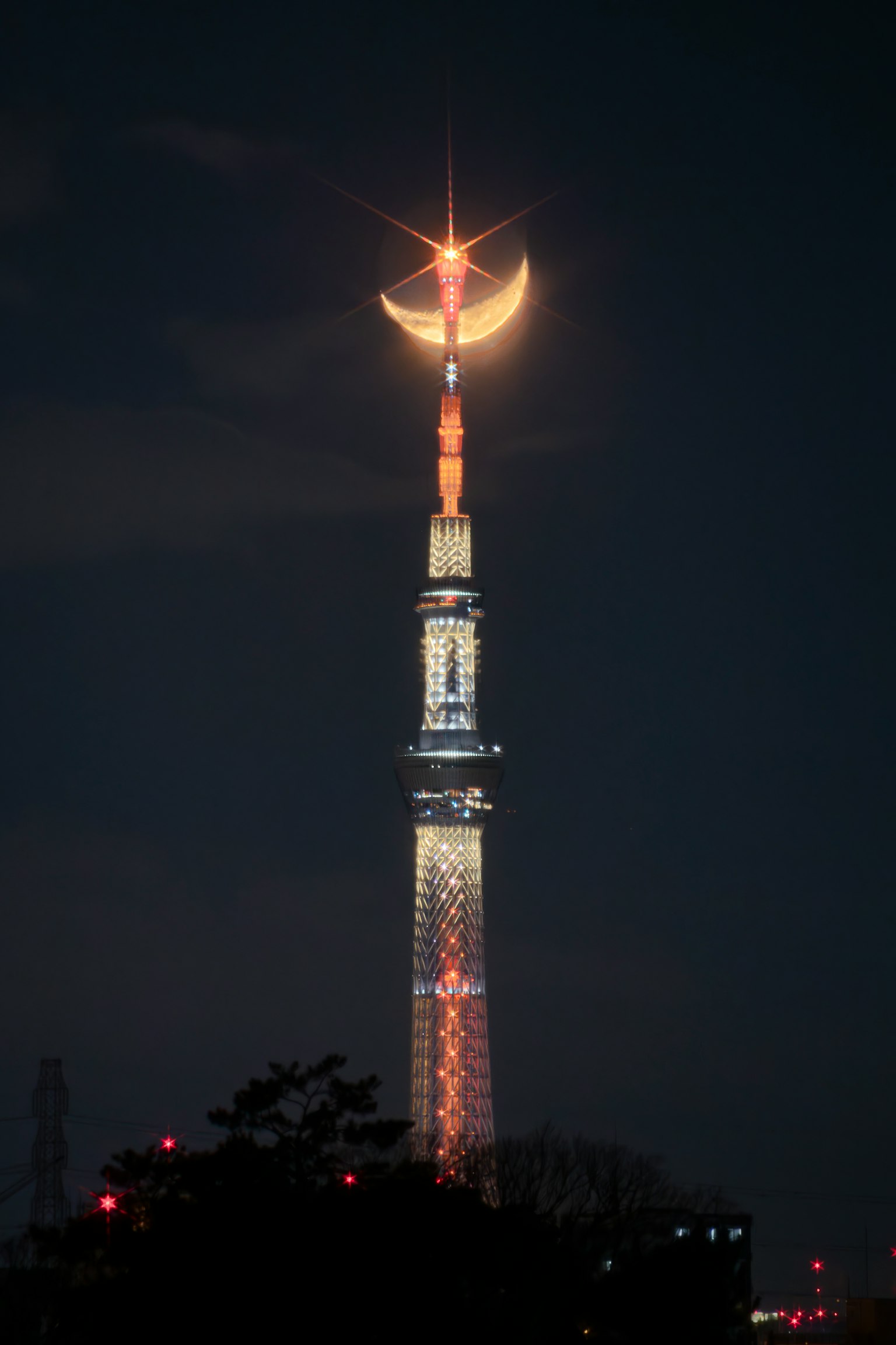 Tokyo Skytree iluminado por la noche con una luna creciente
