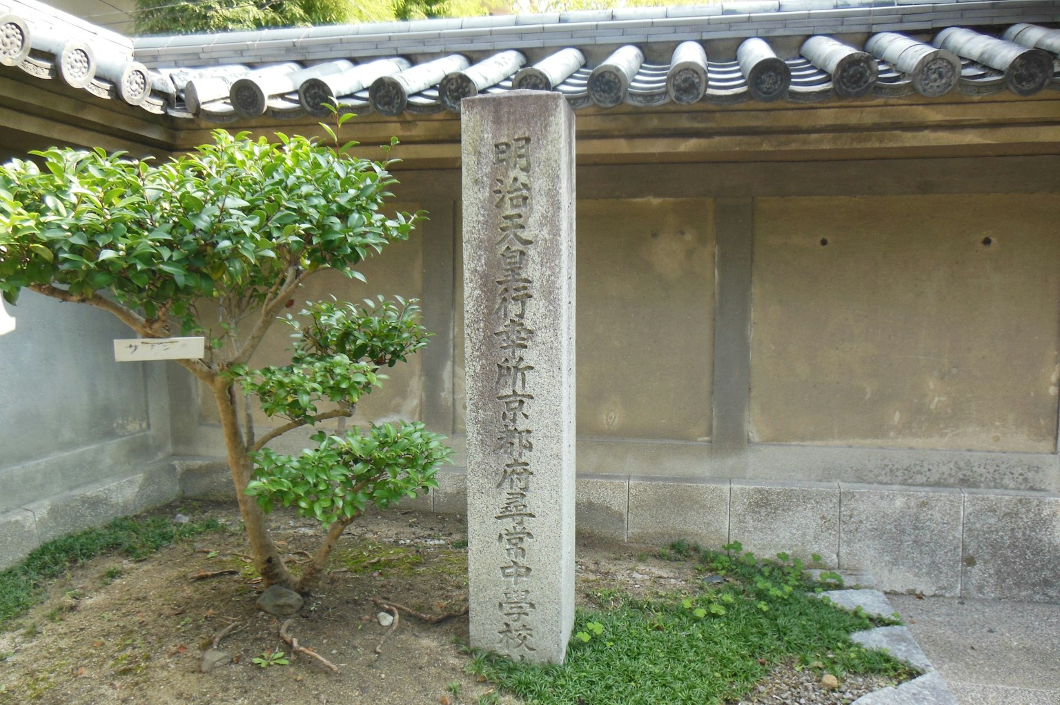 Un espace tranquille avec un monument en pierre et un petit arbre dans le jardin