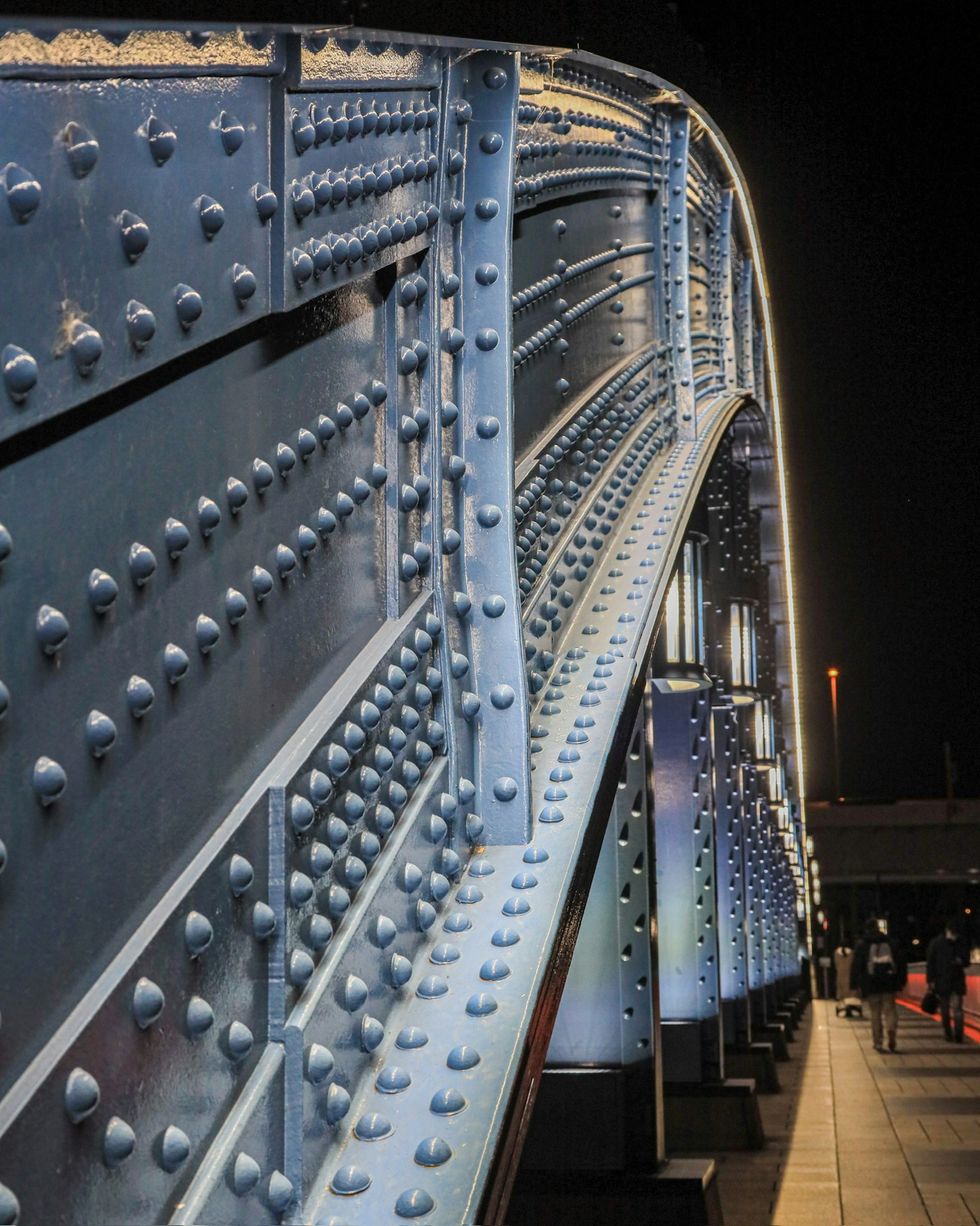 Primo piano di un ponte di notte che evidenzia la struttura metallica e i rivetti