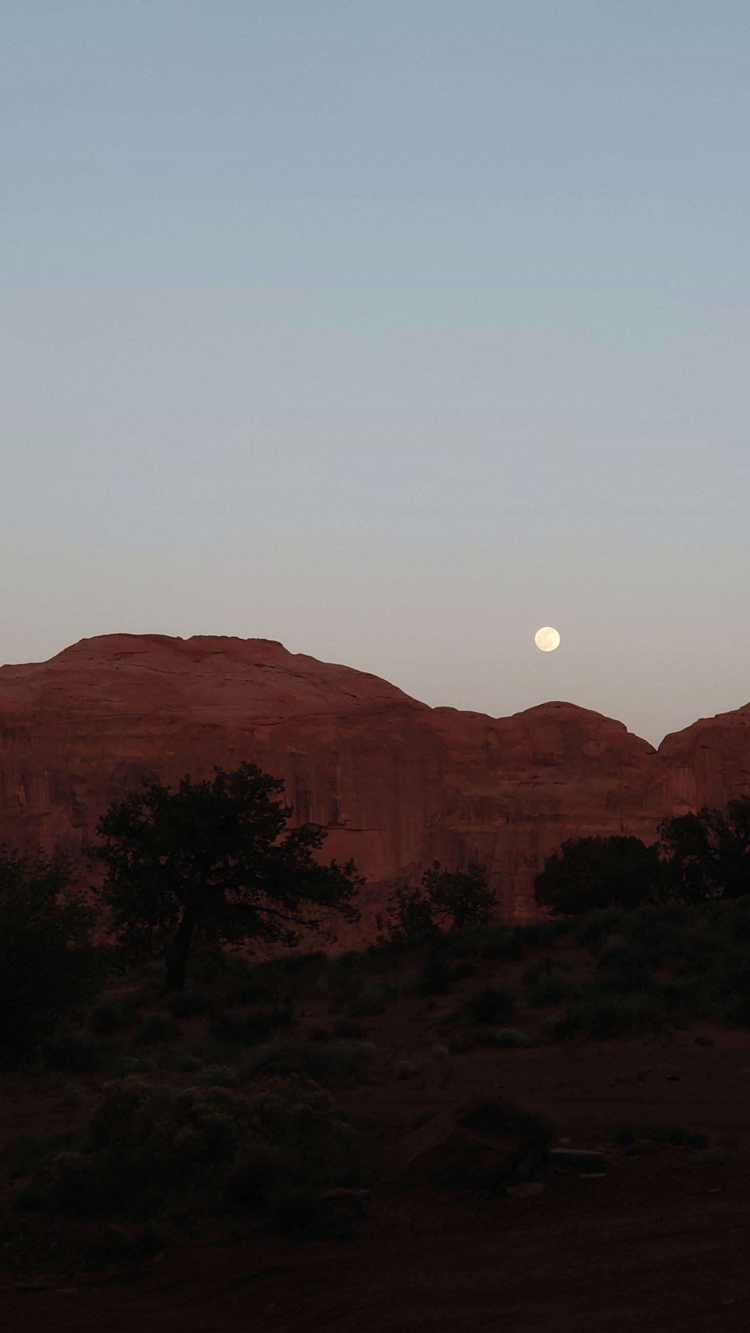 Pemandangan tenang dengan gunung merah dan bulan purnama