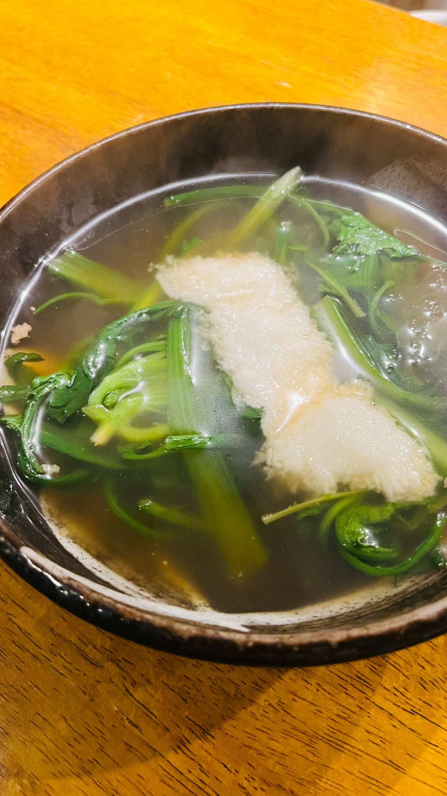 Ciotola di zuppa fumante con verdure fresche e pesce bianco