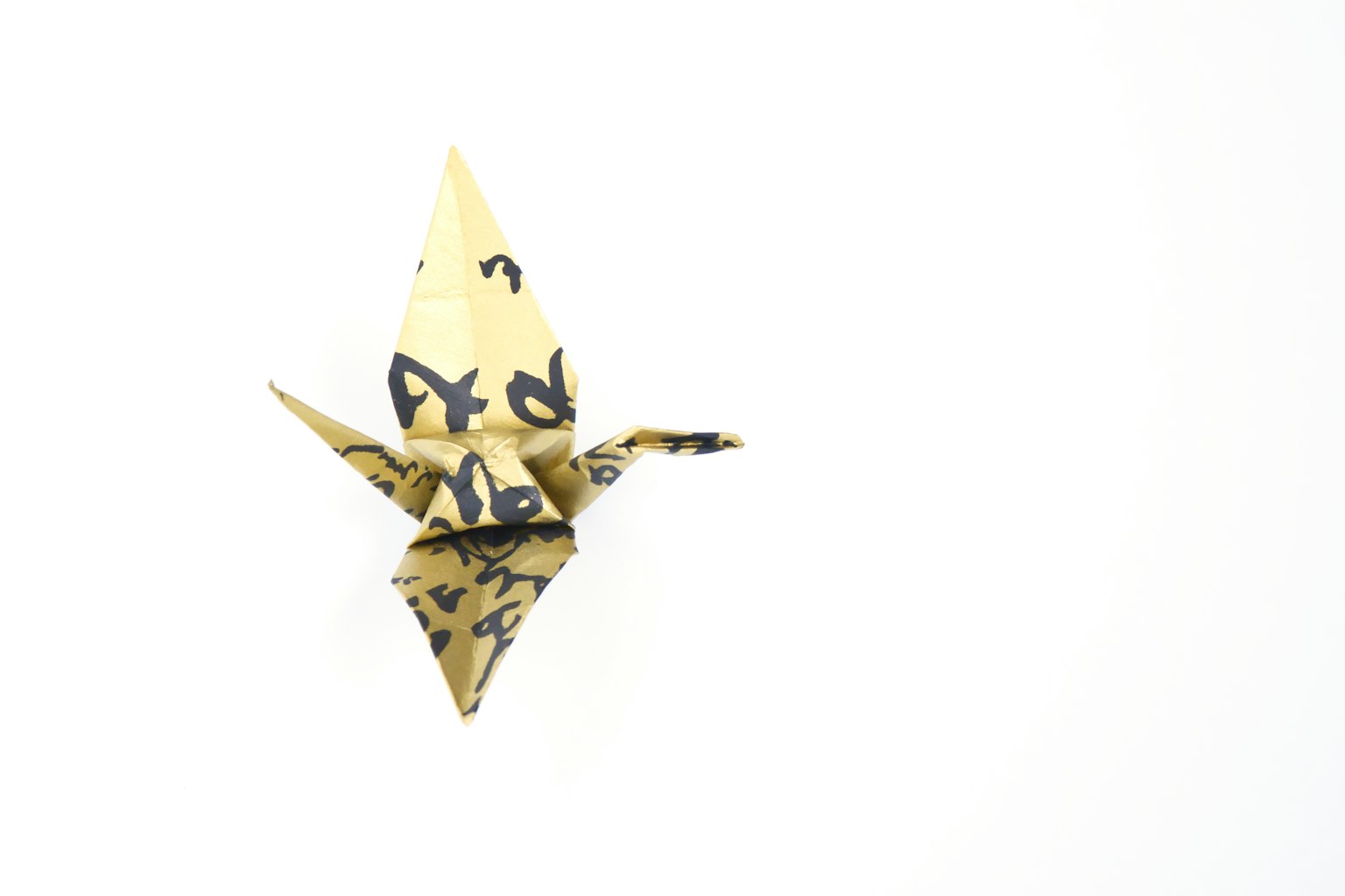 Una grulla de origami de papel amarillo con patrones sobre un fondo blanco