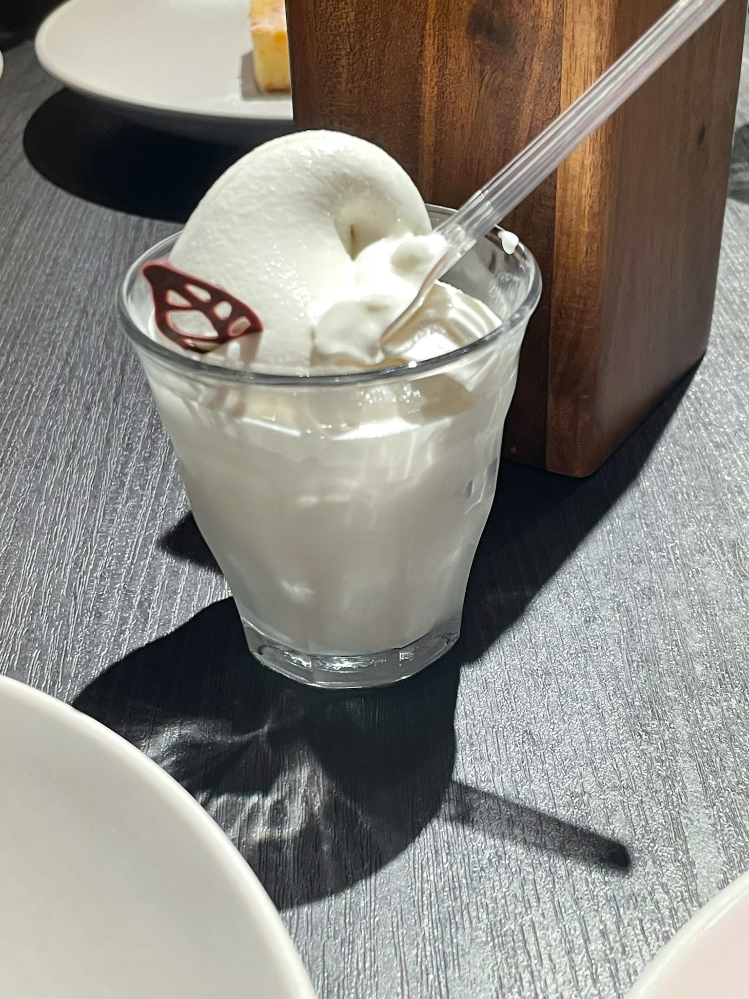 Gelas transparan dengan es krim putih dan sedotan plastik