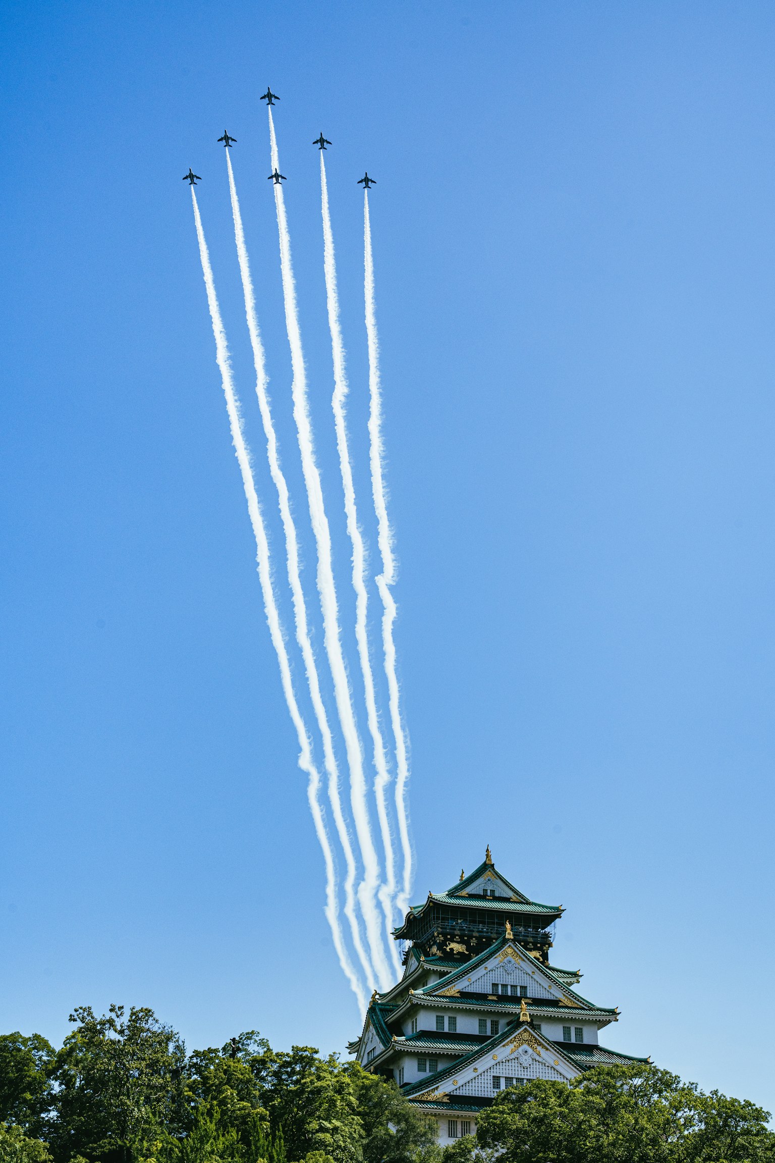 Osaka Schloss unter einem klaren blauen Himmel mit Rauchspuren von fliegenden Flugzeugen