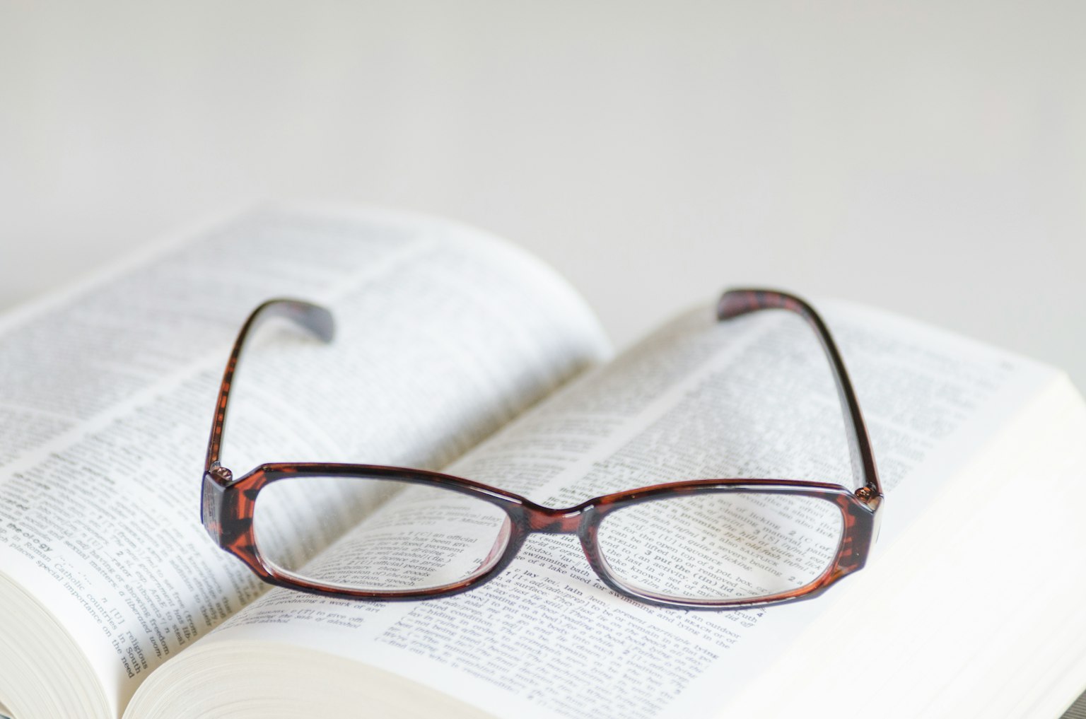 Primer plano de gafas marrones descansando sobre un libro abierto