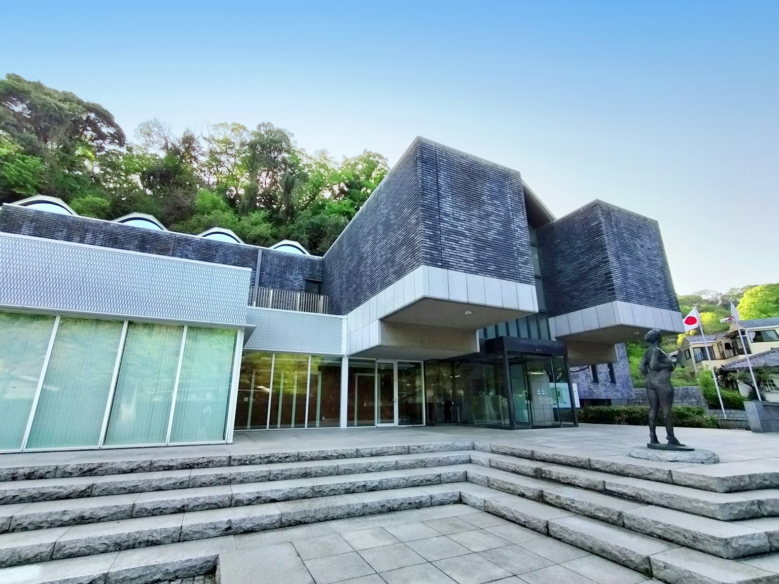 Außenansicht eines modernen Architekturmuseums umgeben von üppigem Grün