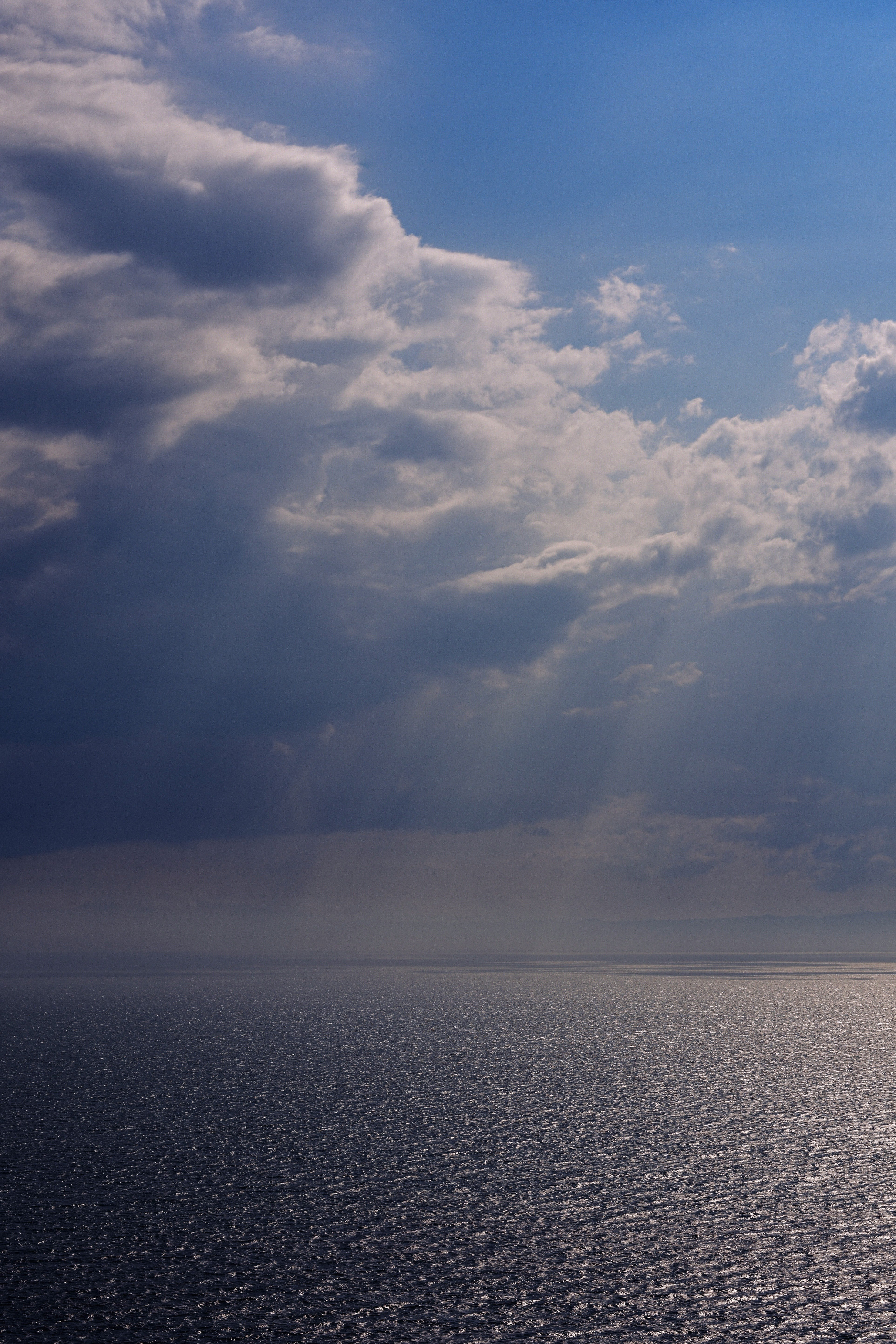 青い空と雲の下に広がる海面の光