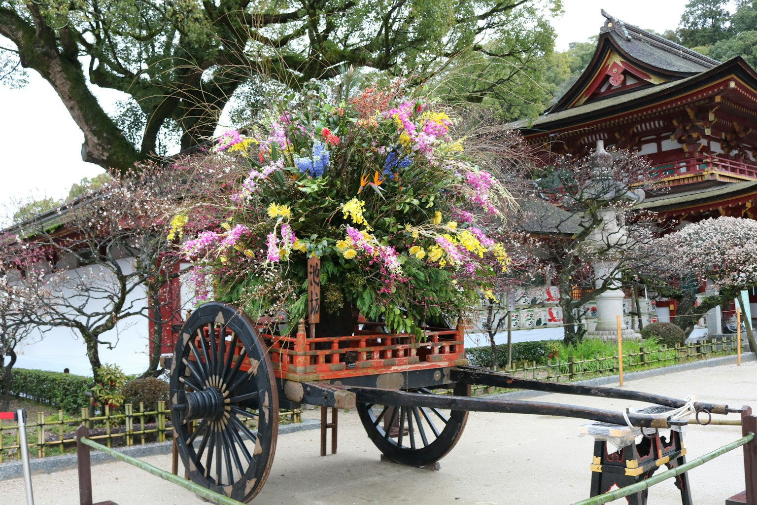 Carretto in legno tradizionale pieno di fiori colorati e edificio giapponese sullo sfondo
