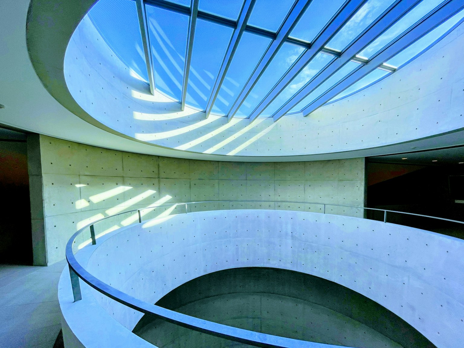 Interior de un edificio moderno con una escalera curva y luz natural de un techo de vidrio