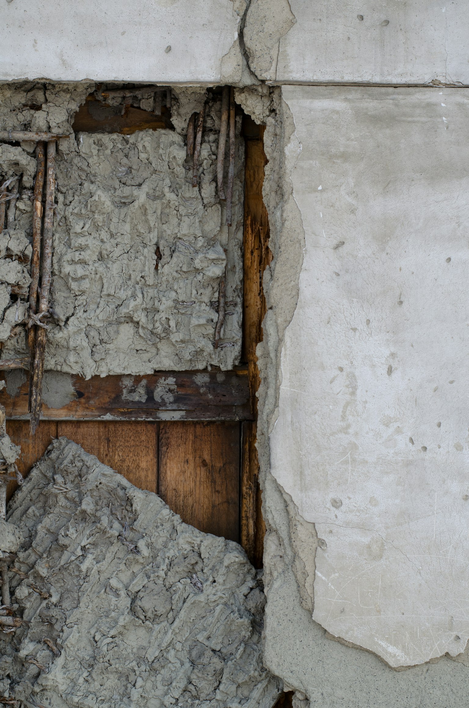 Section exposée d'un mur montrant du béton fissuré et des poutres en bois