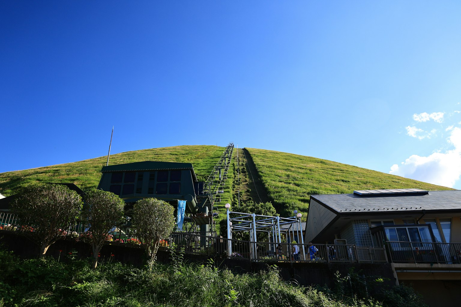 Vue pittoresque d'une colline verte sous un ciel bleu avec un petit bâtiment à la base