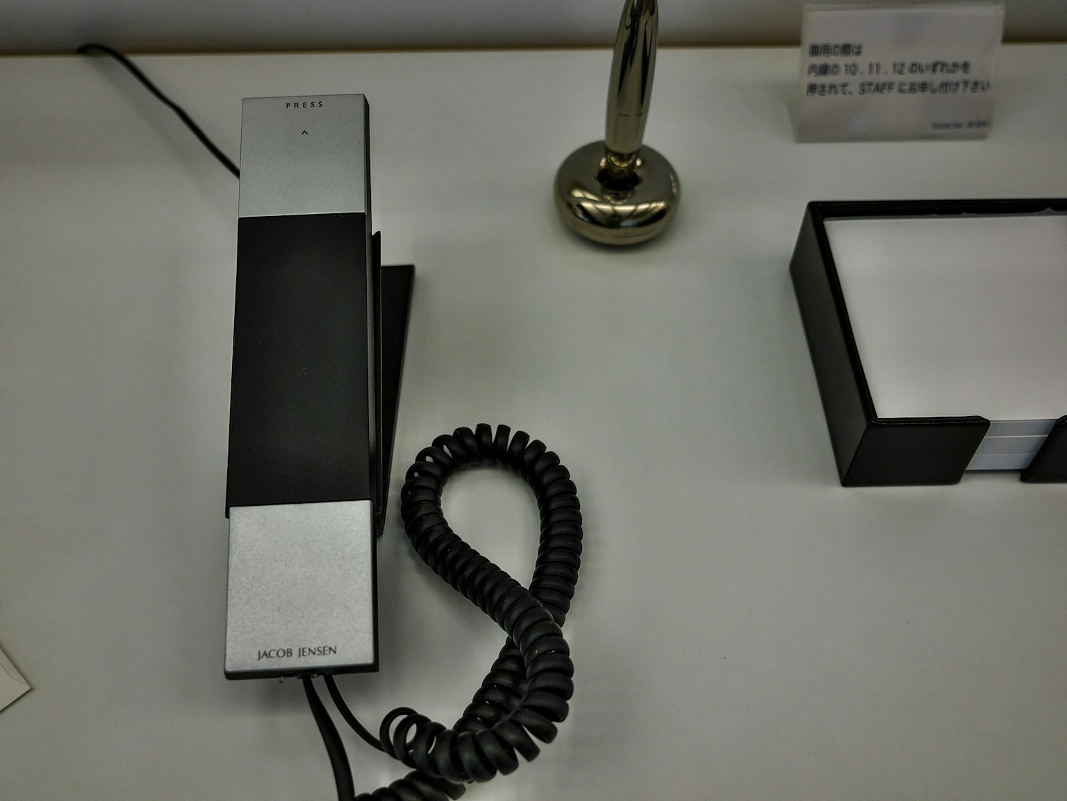 A black telephone handset and a silver stand on a desk