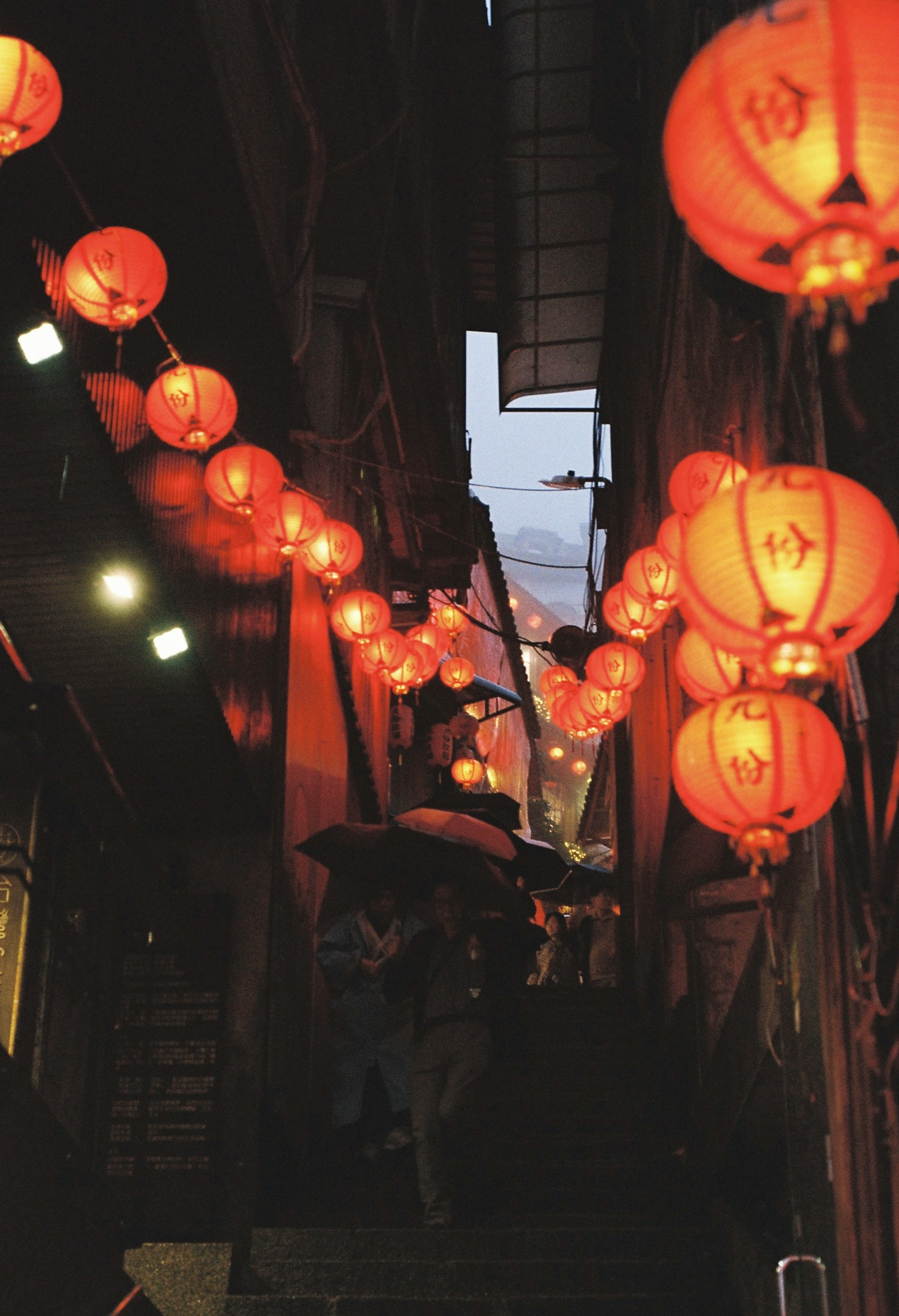 alley storefront with rows of red lanterns in the rain