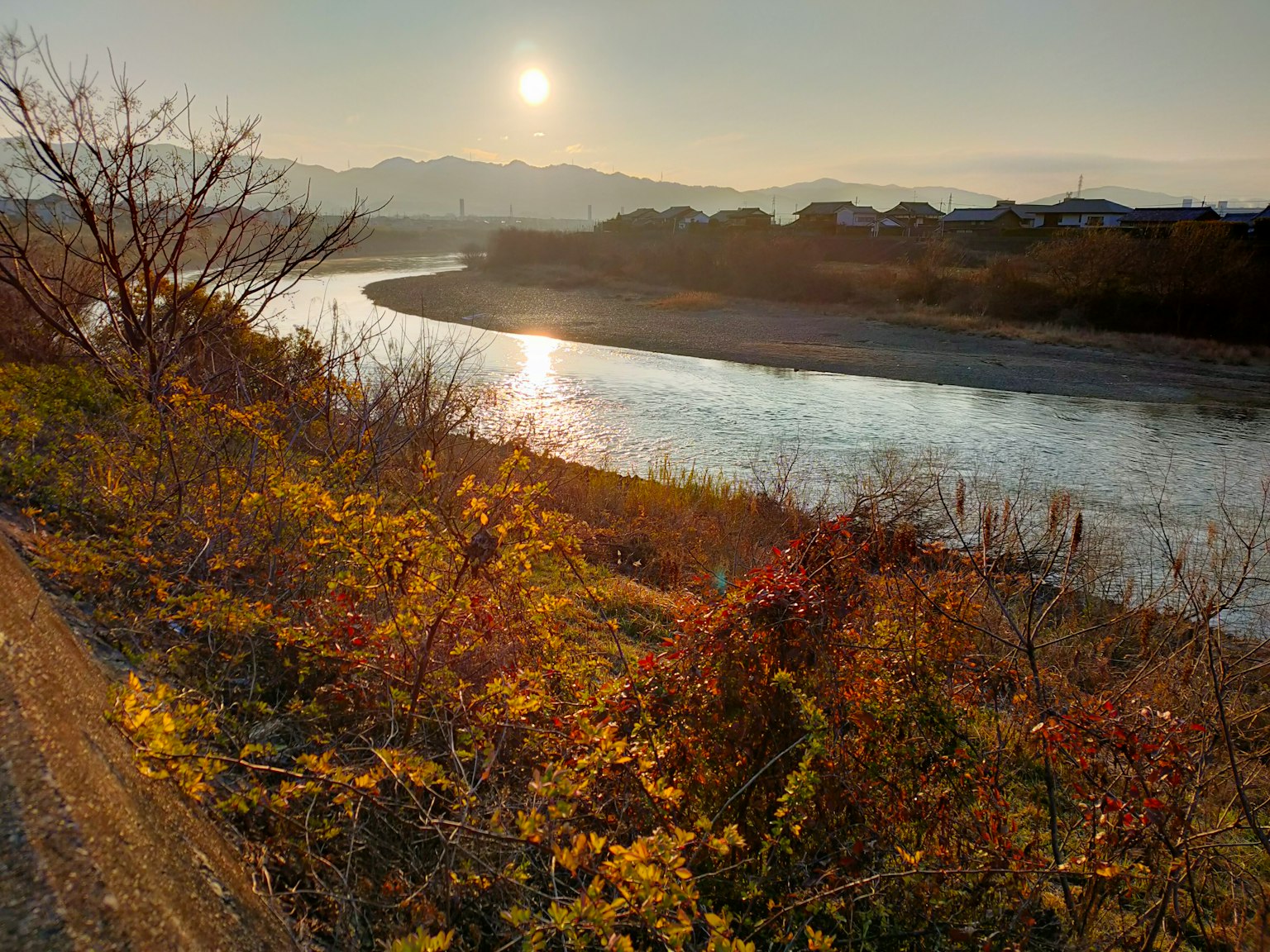 Ruhige Flusslandschaft mit herbstlichem Laub Sonnenuntergang hinter den Bergen