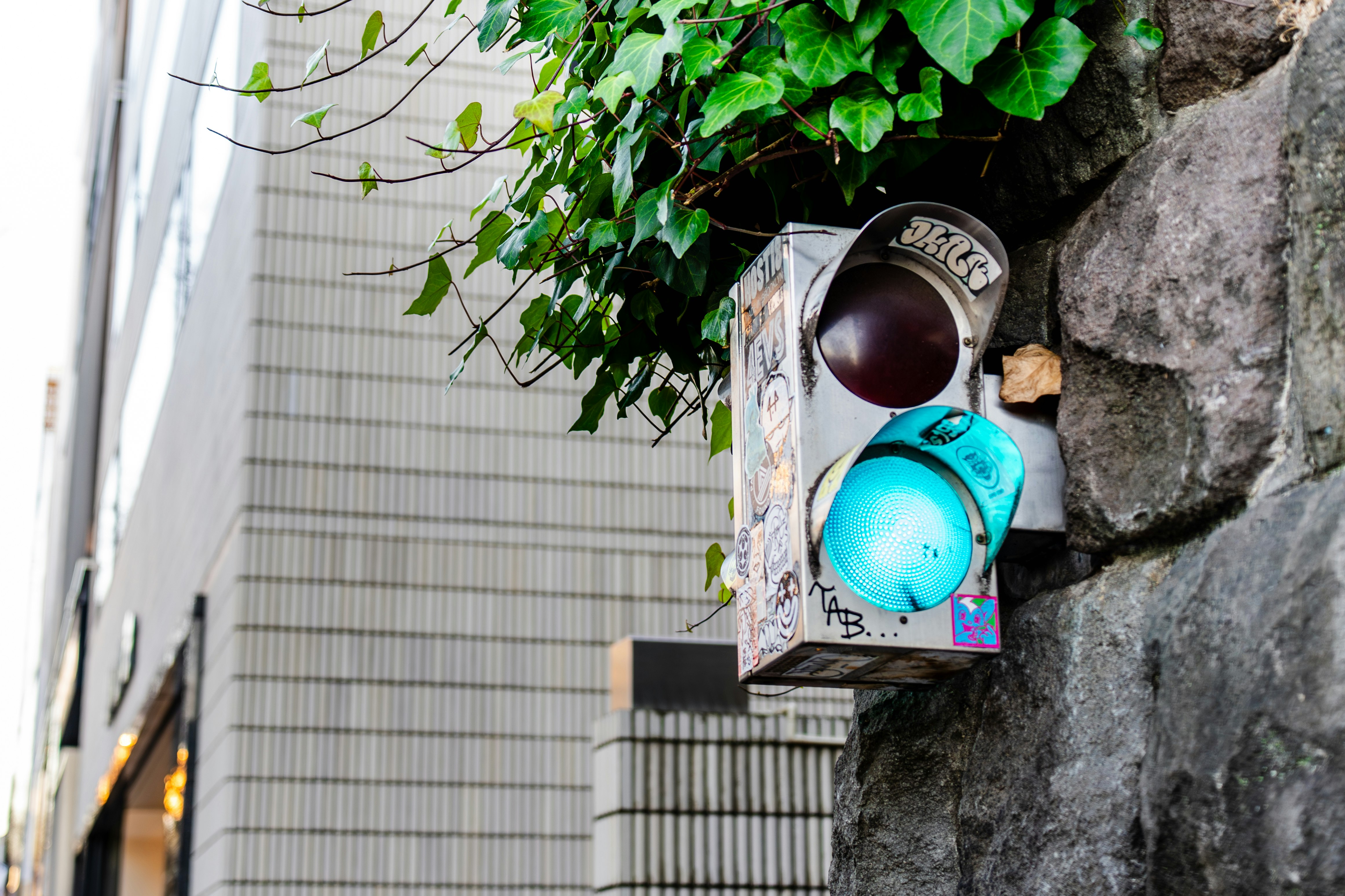 alley corner with a blue lantern and wall-mounted street light on a stone wall