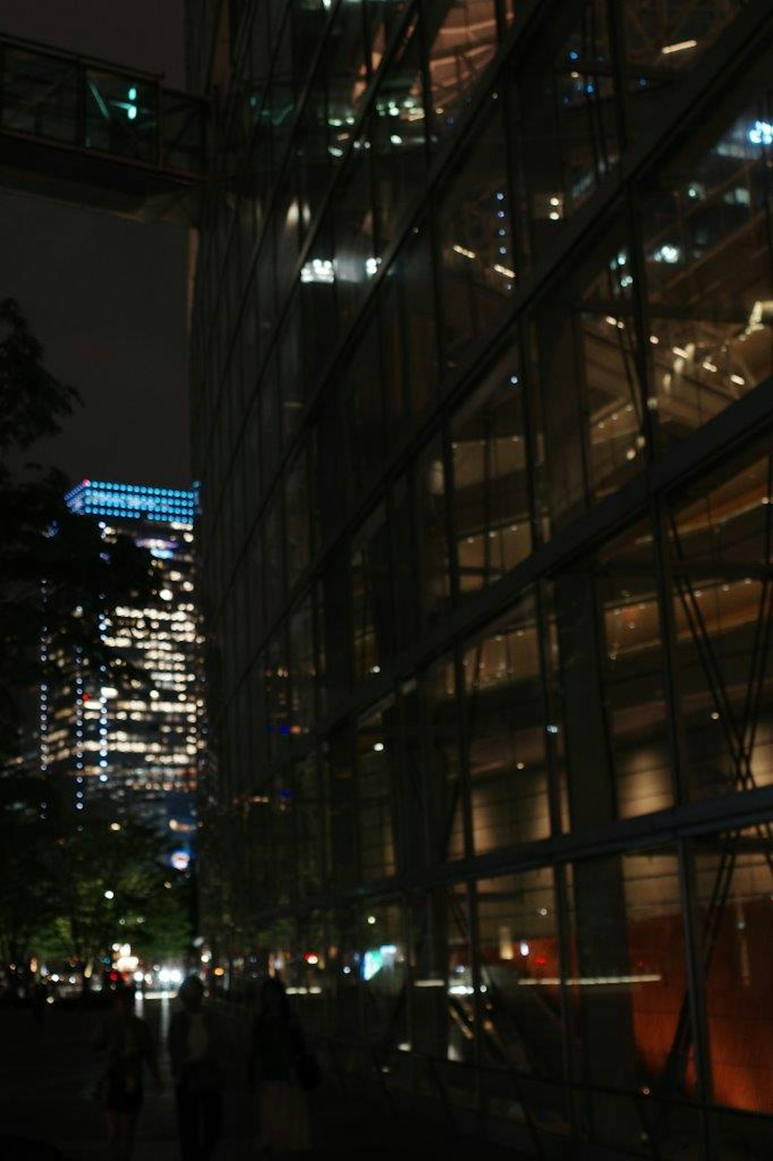 Illuminated glass building in a nighttime urban landscape with surrounding lights
