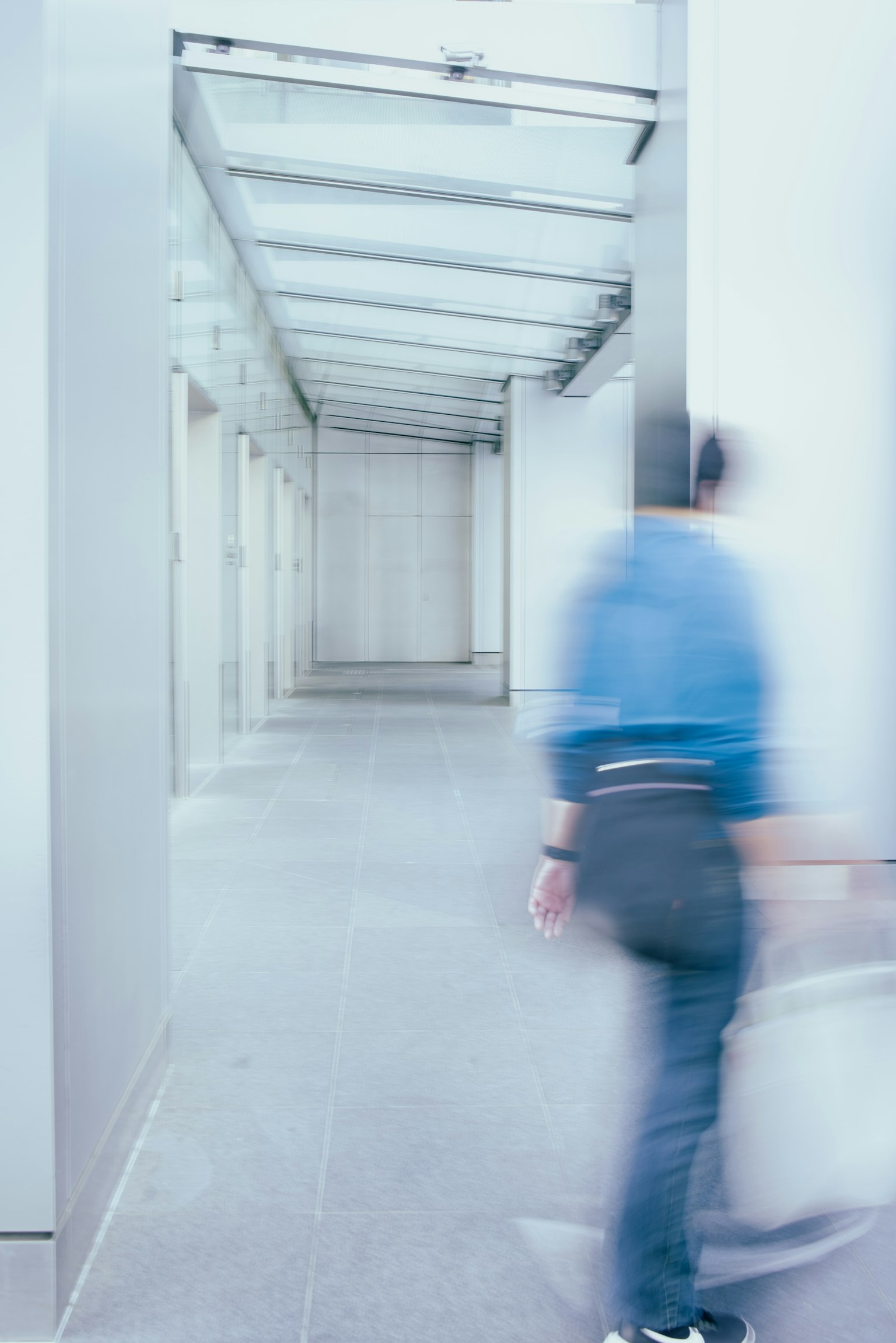 A blurred figure walking through a modern corridor
