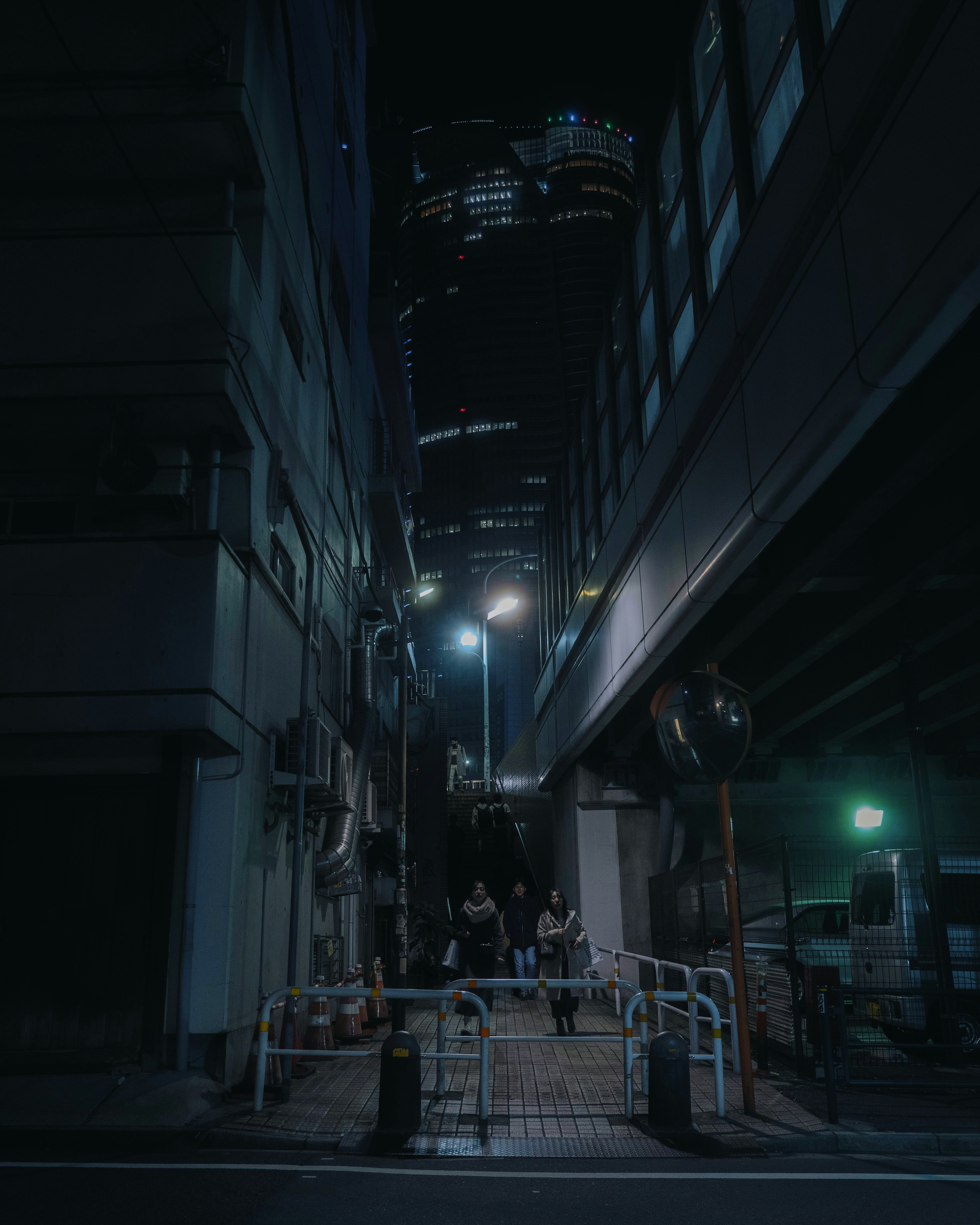 夜の高層ビルが見える狭い路地の街並み
