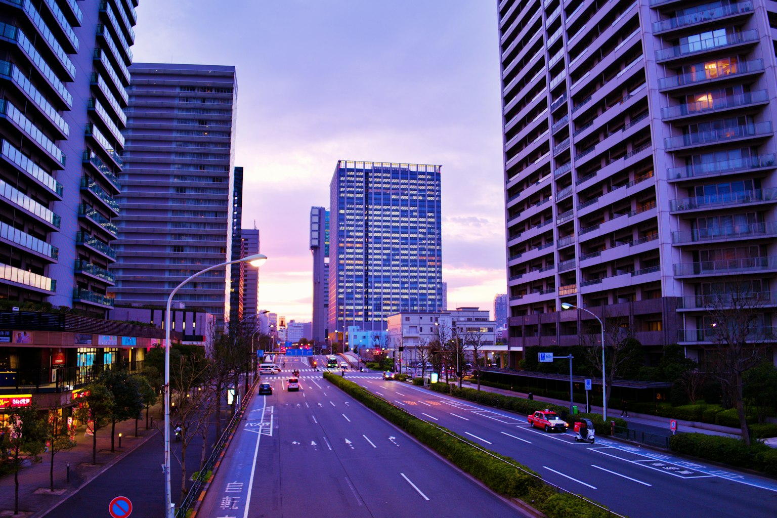 Urban skyline at dusk featuring tall buildings and a serene street