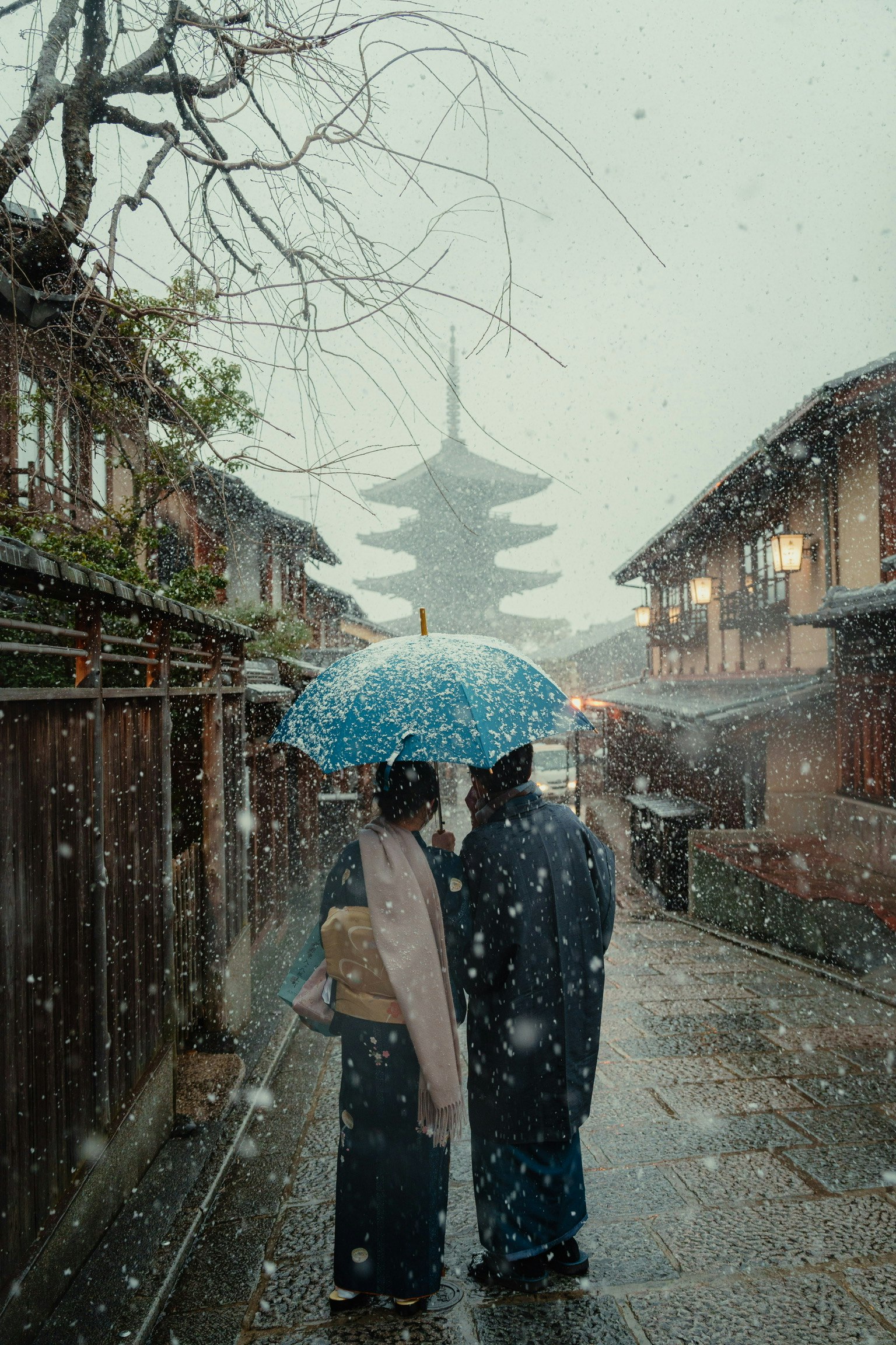 雪中一對情侶撐傘背景為傳統建築和一座塔