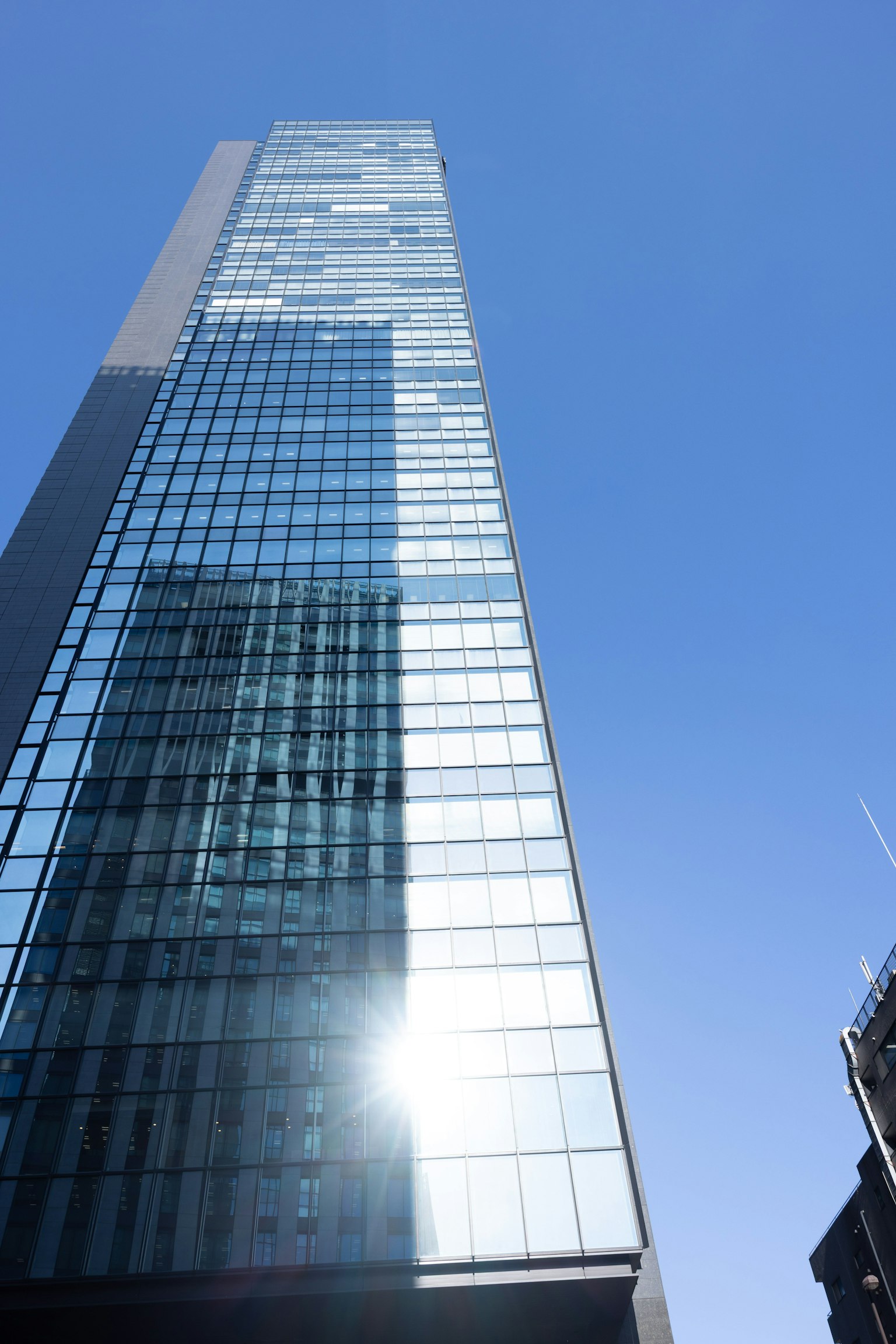 Gratte-ciel avec façade en verre reflétant le ciel bleu