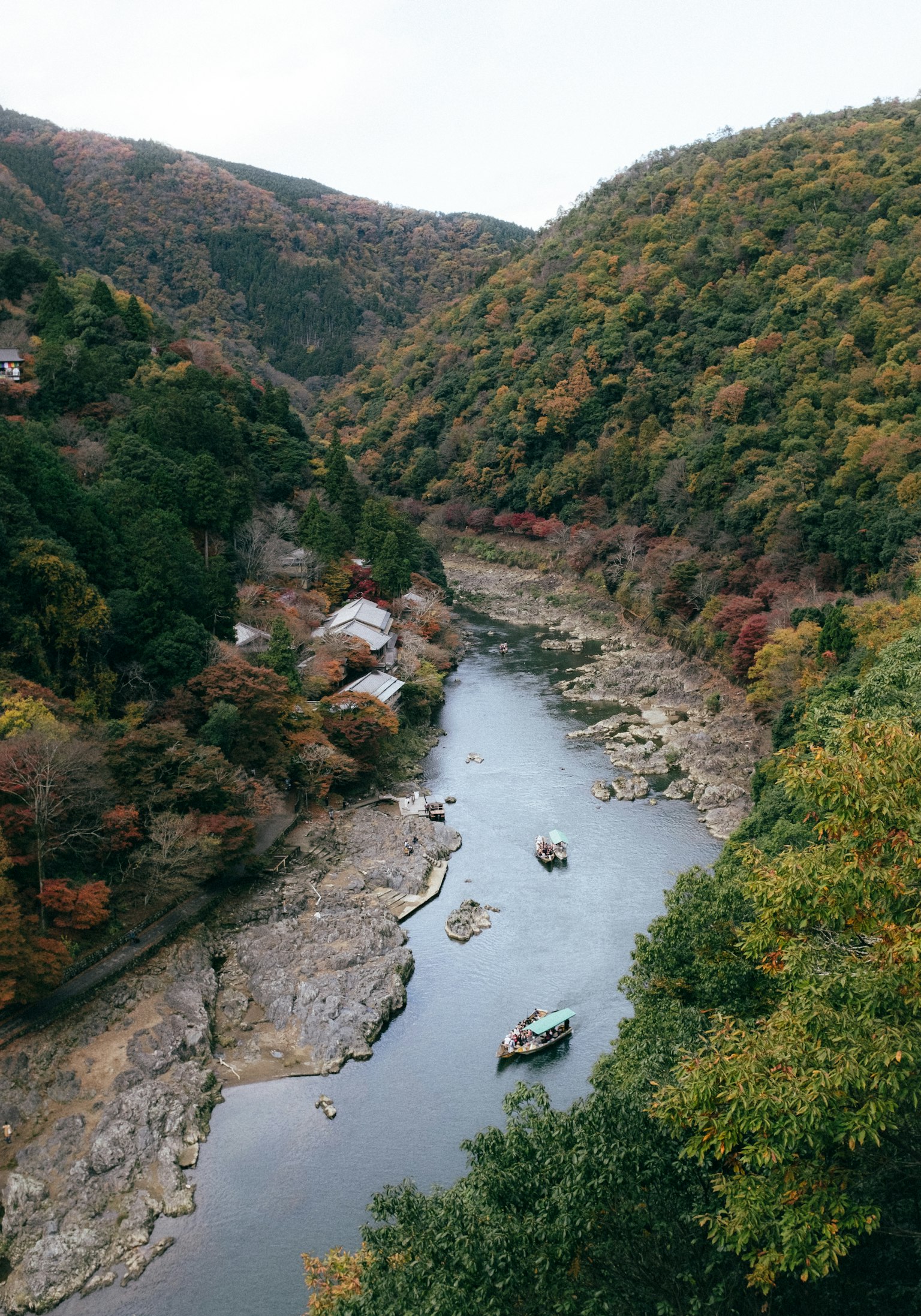 Malersiche Aussicht auf Berge in Herbstfarben mit einem ruhigen Fluss und Booten