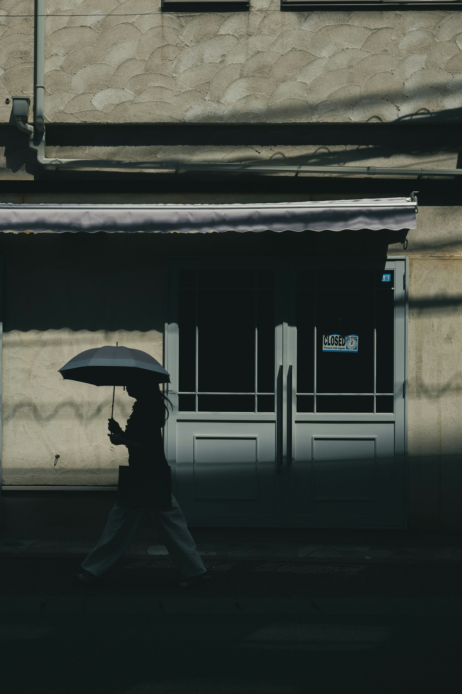 Người đi bộ với ô trước một tòa nhà