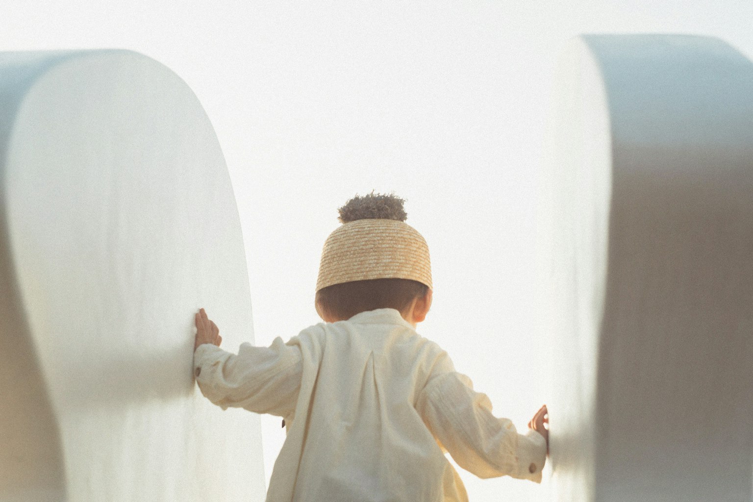Un enfant en tenue blanche explorant entre de grandes formes blanches