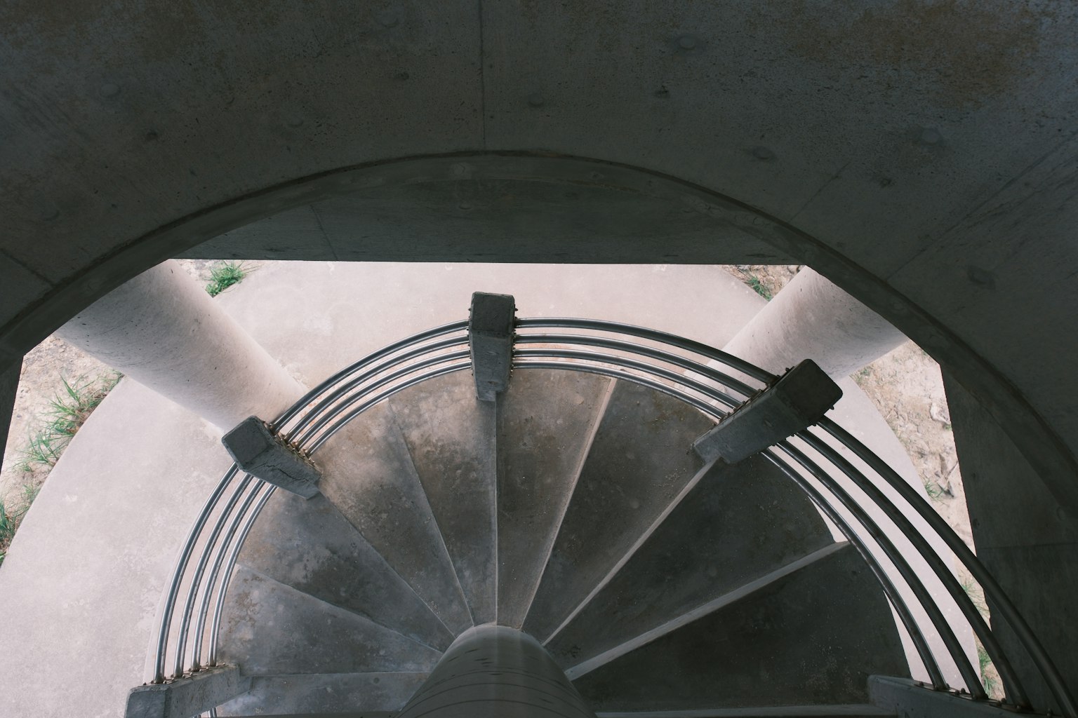 Vue d'en haut d'un escalier en colimaçon montrant une structure en béton et des colonnes