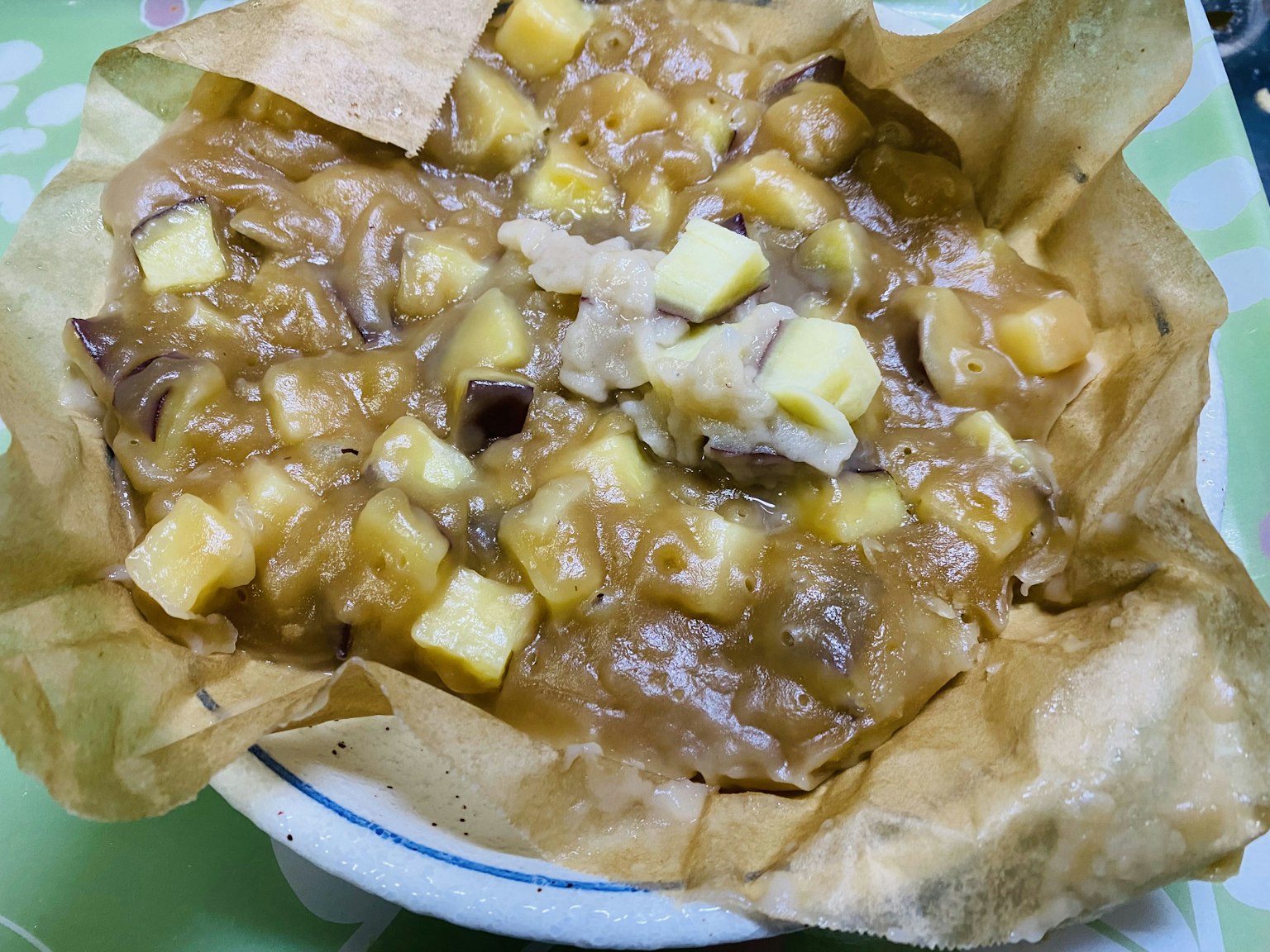 Puding apel karamel hangat disajikan dalam mangkuk dengan apel dadu dan saus karamel