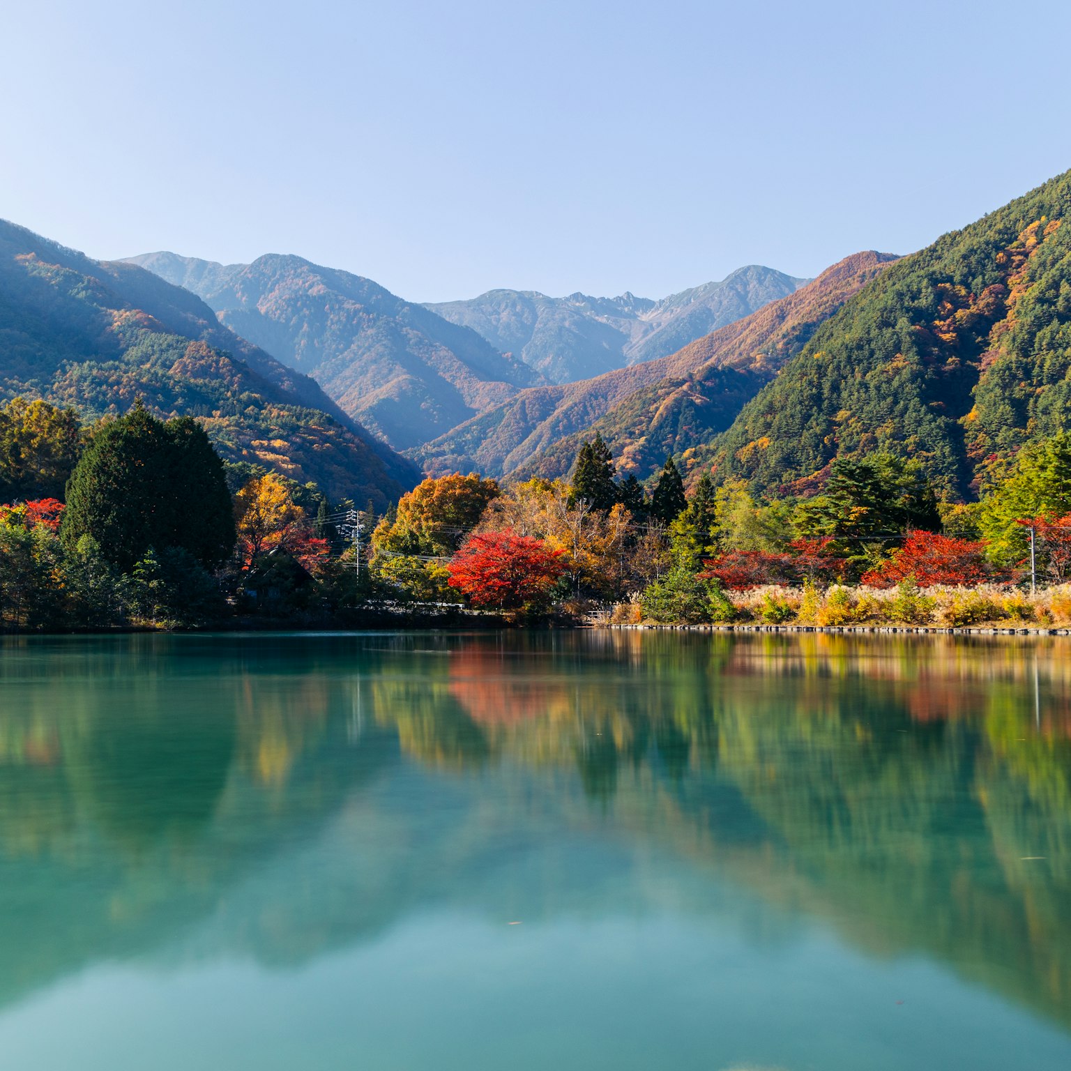 寧靜湖泊周圍秋葉和山脈的風景
