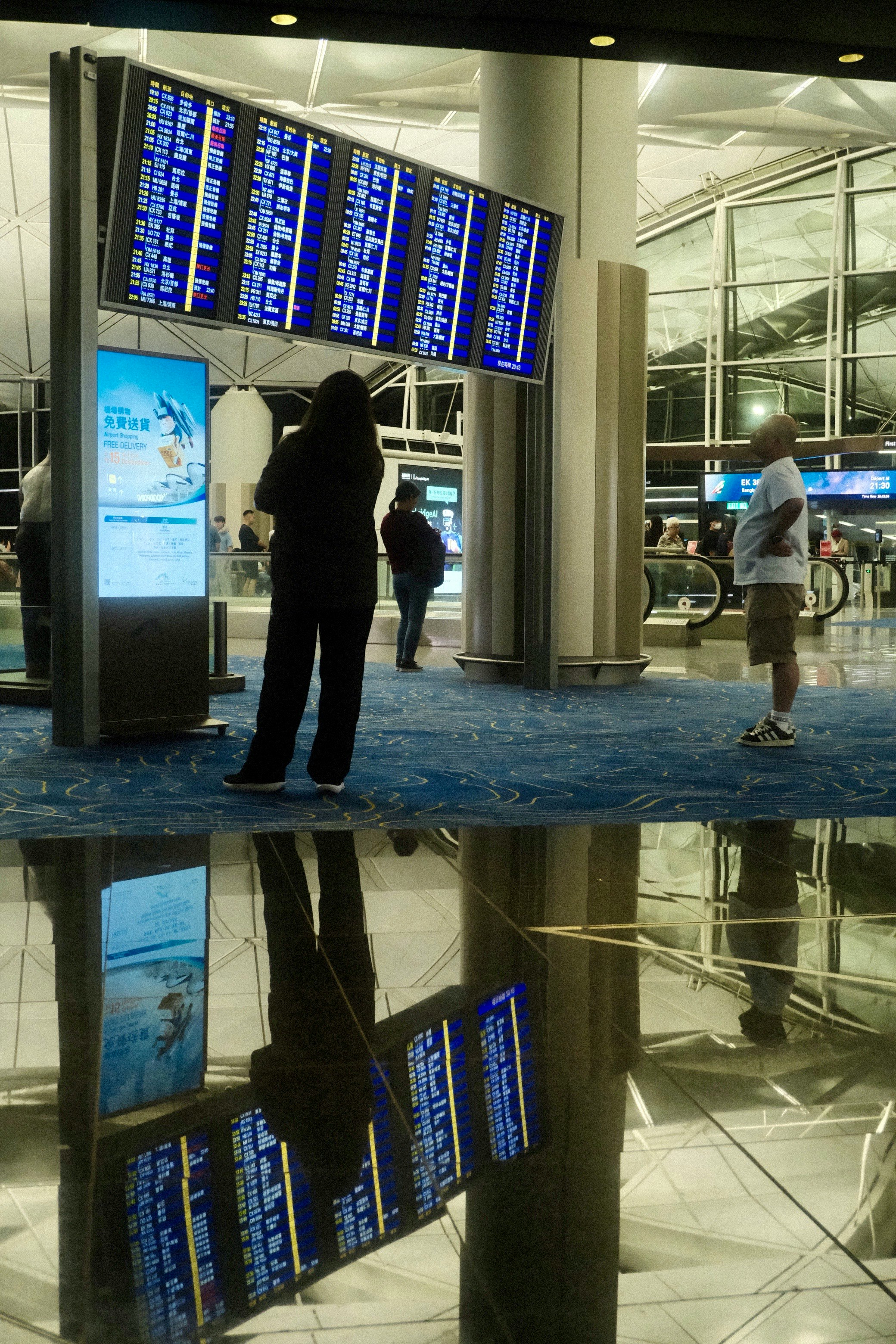 personas mirando pantallas de información en una sala de llegadas del aeropuerto