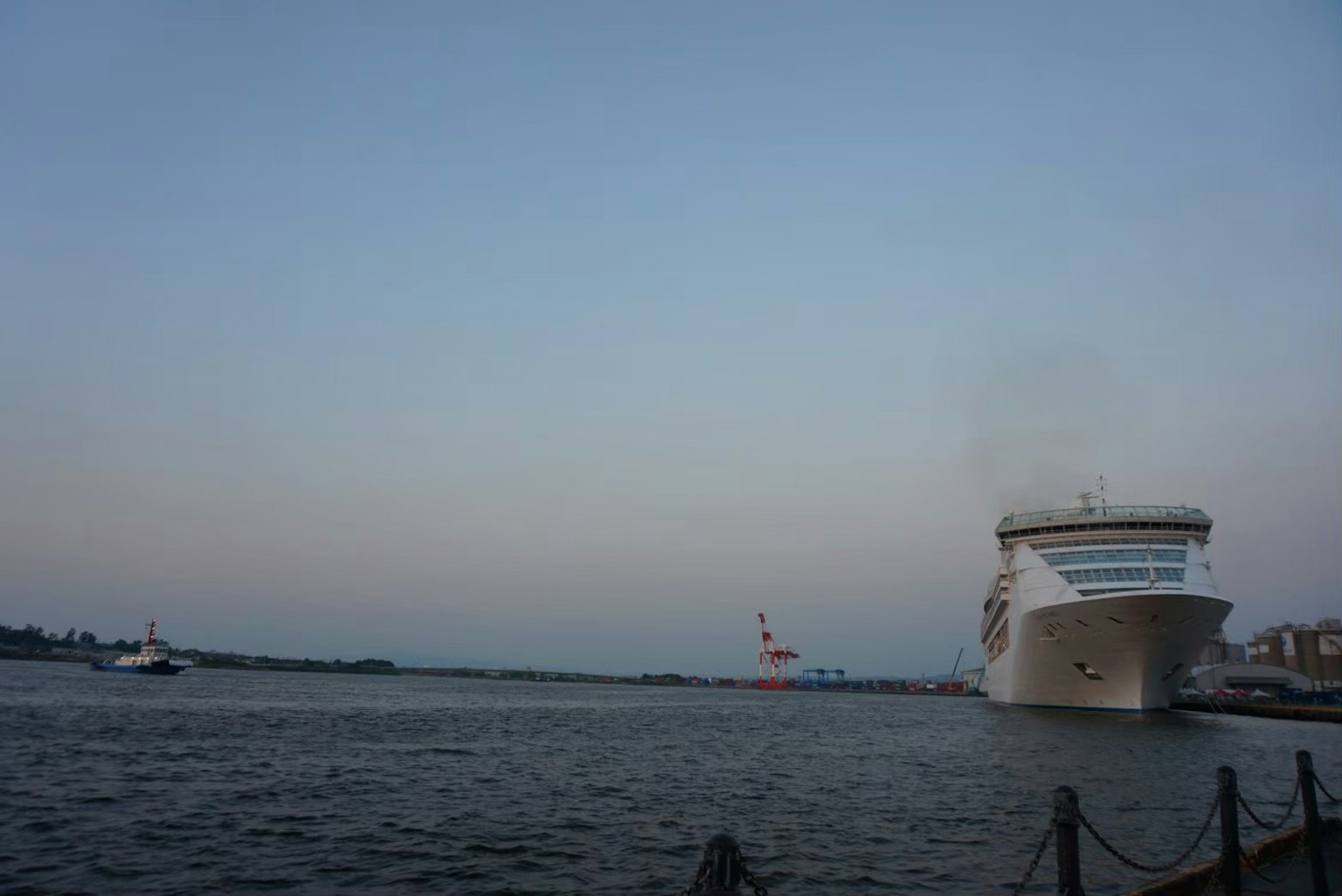 Large cruise ship on the water near the port at dusk with a calm sky
